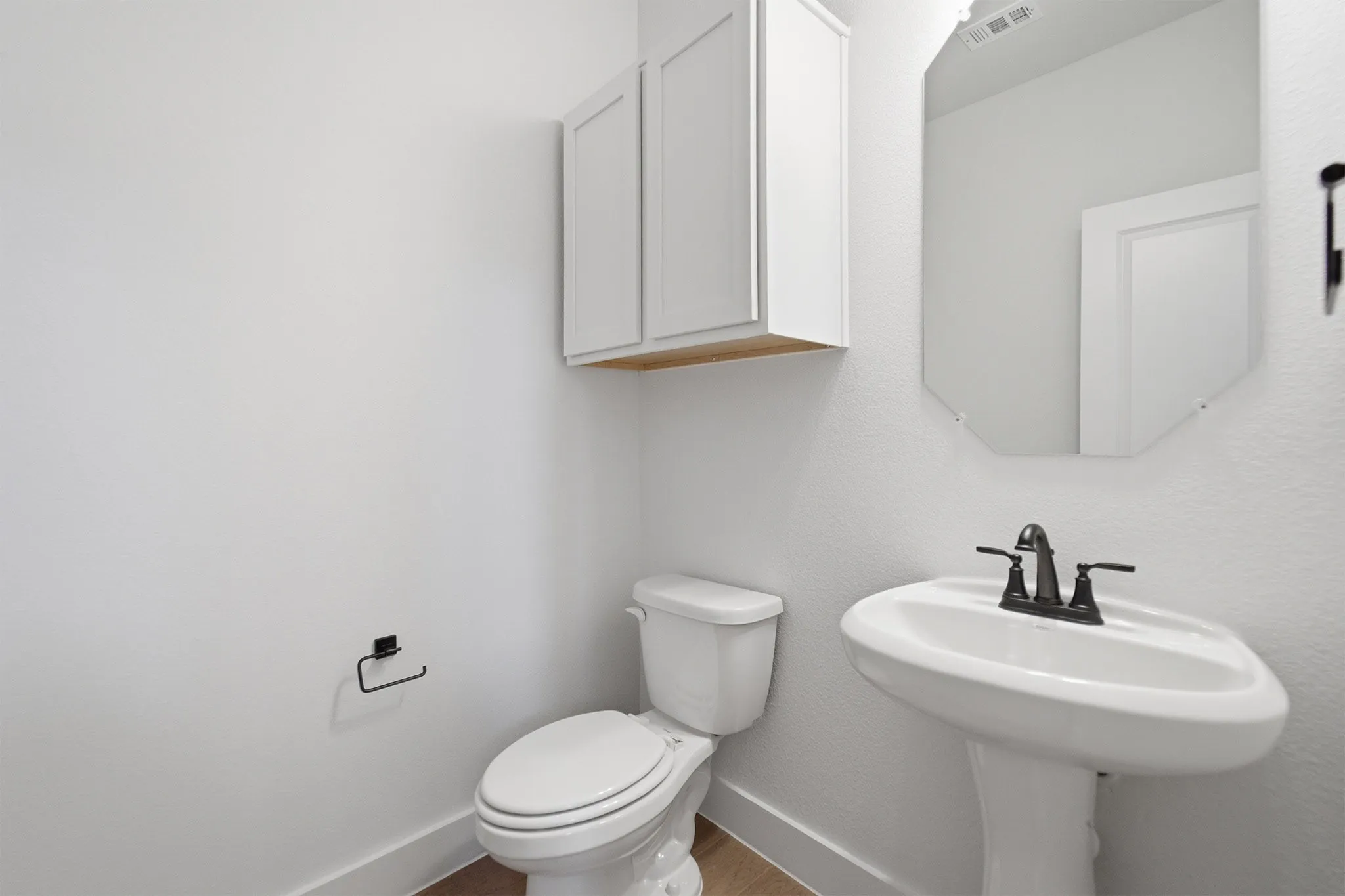 Pedestal sink with black-finish faucet and octagonal mirror