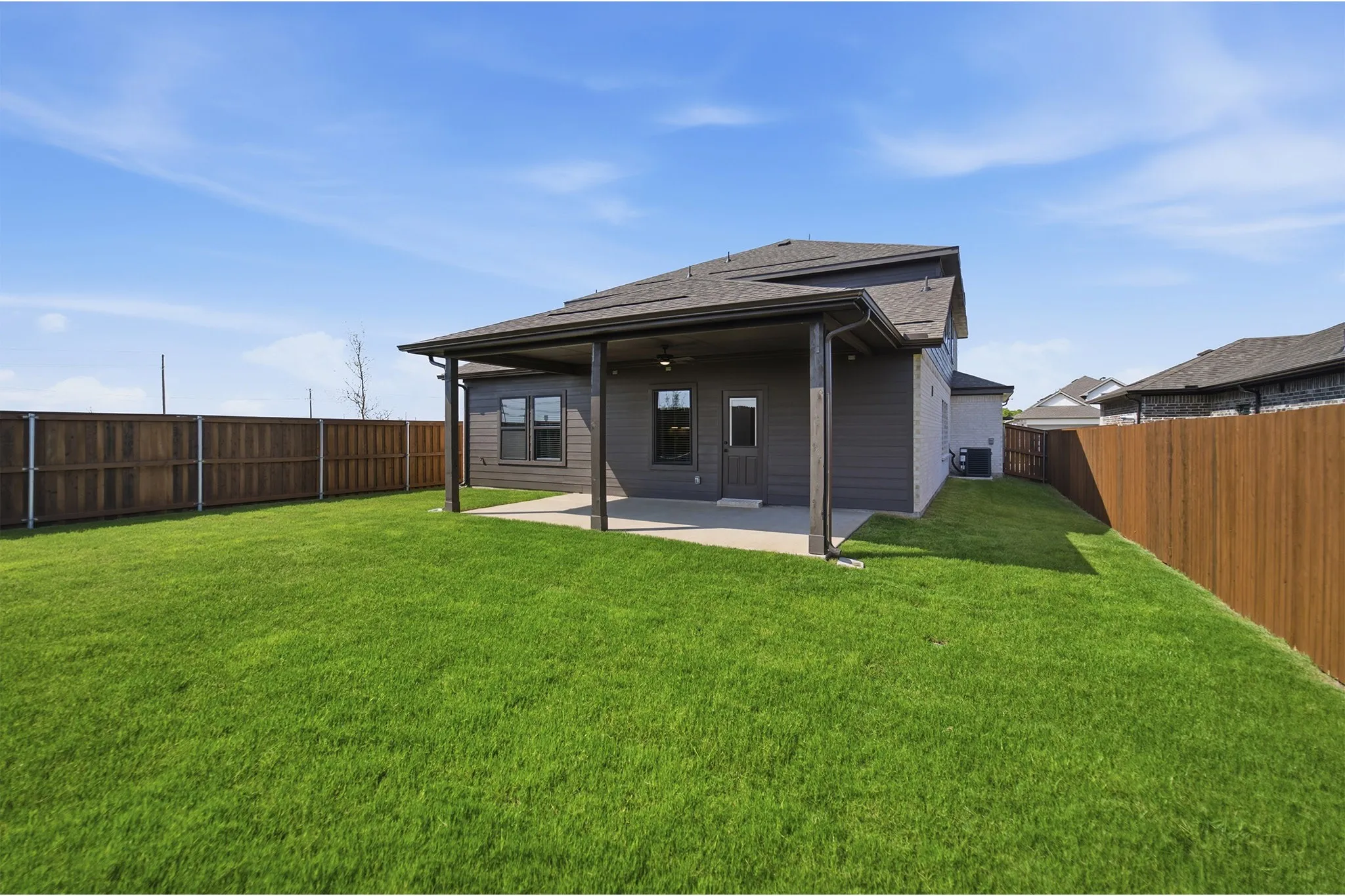 Expansive green lawn with a covered patio, featuring a ceiling fan and recessed lighting