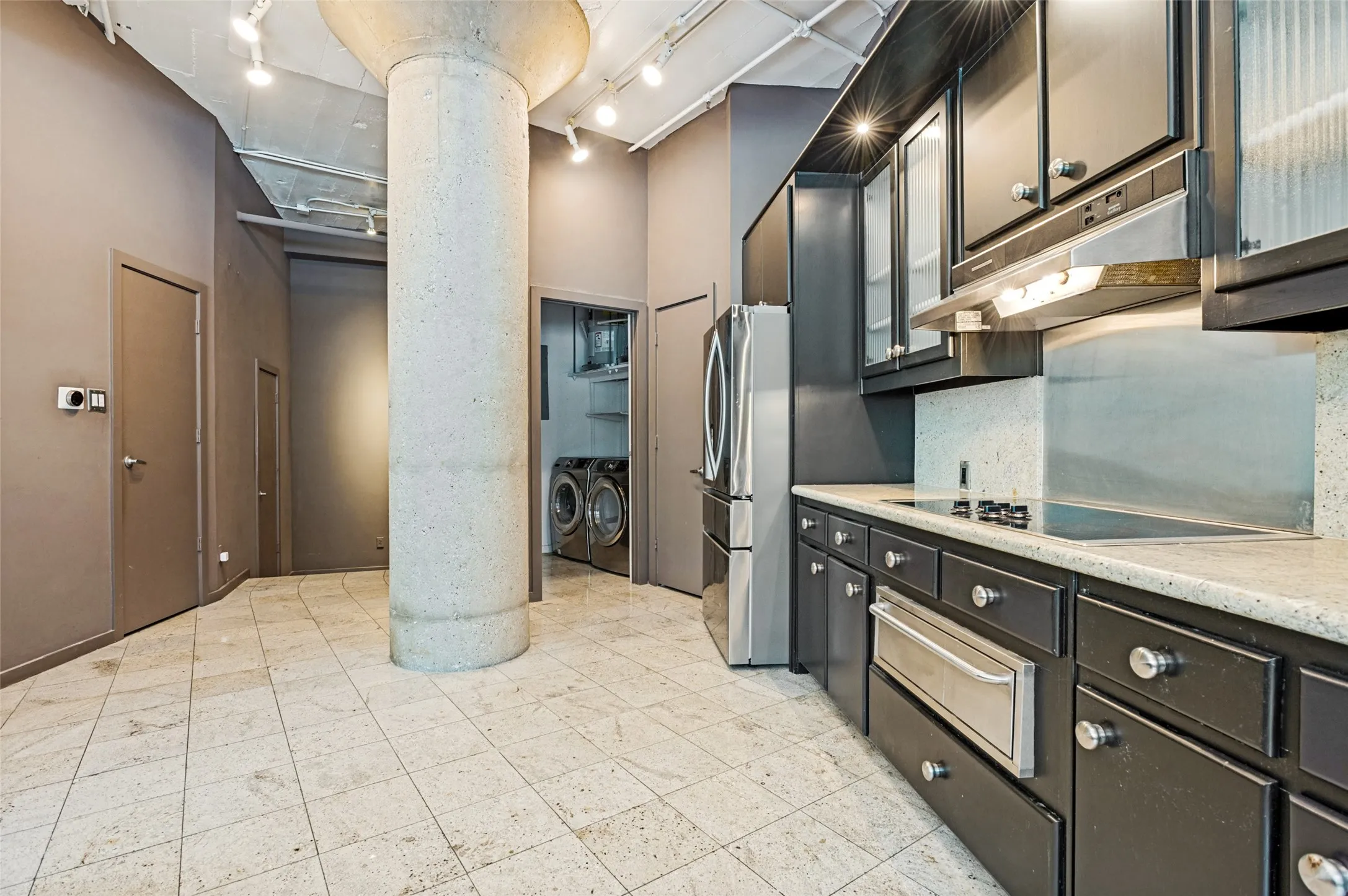 Kitchen featuring dark cabinetry, stainless steel appliances, and a light-toned countertop