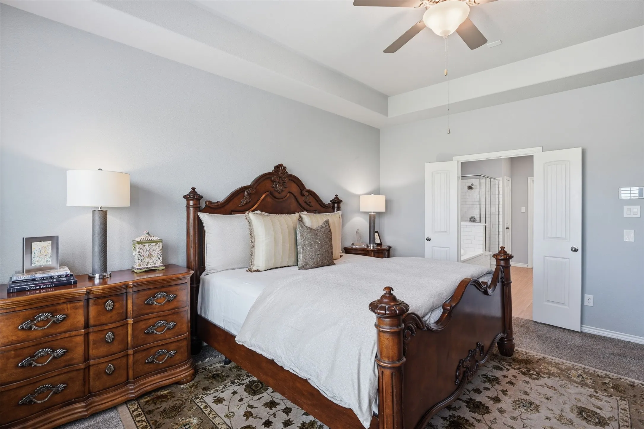 Spacious bedroom featuring light gray walls and a tray ceiling