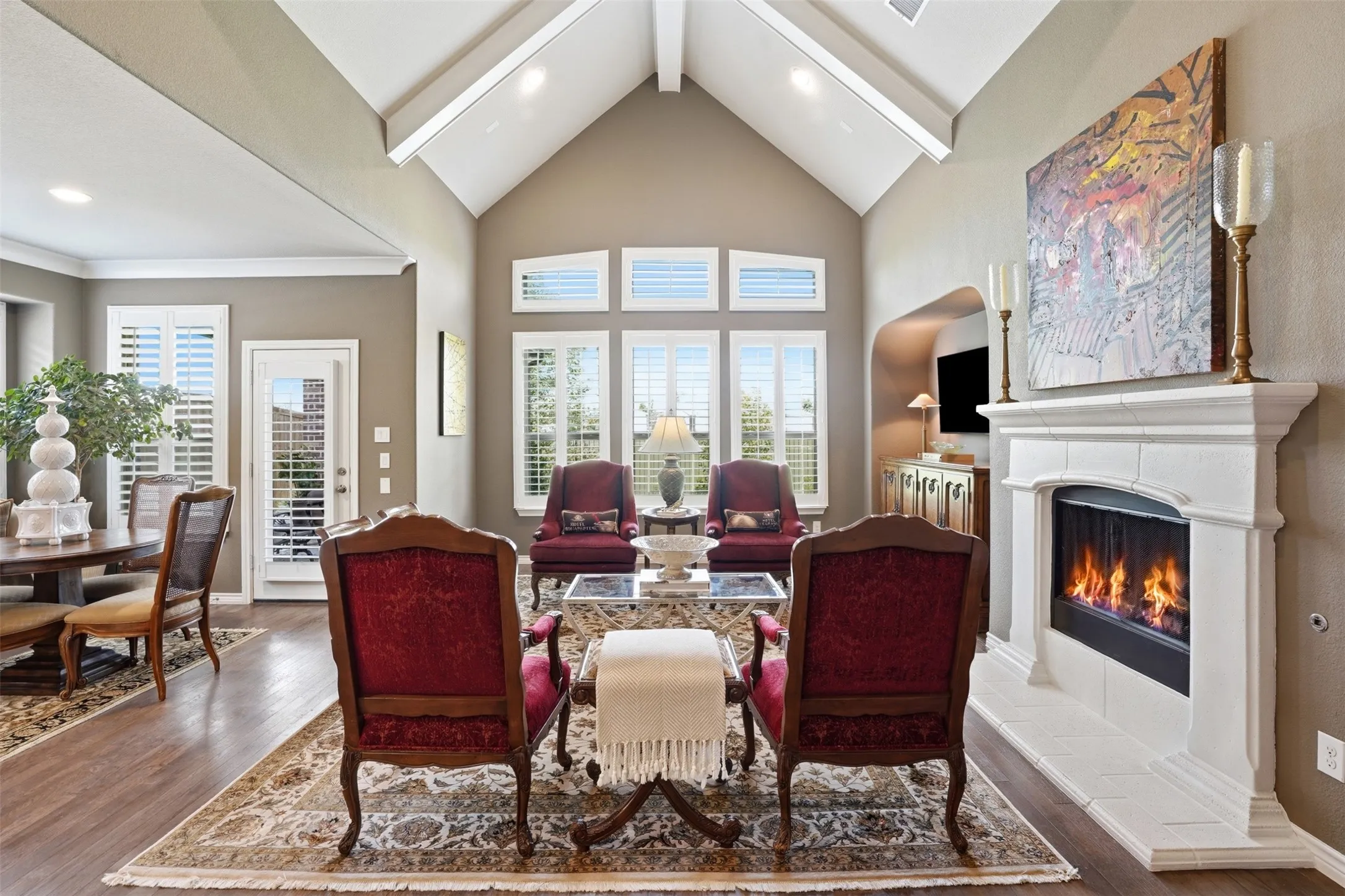 Living area featuring a vaulted ceiling with exposed beams, wood-finish flooring, and a fireplace with a detailed mantel