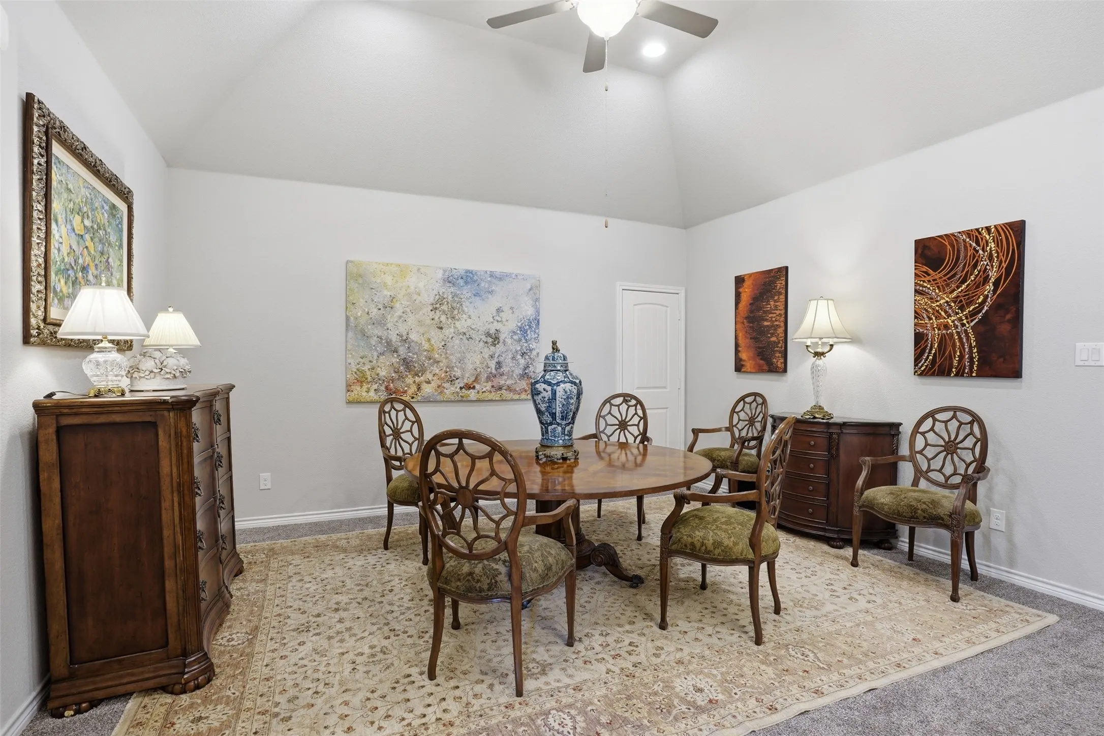 Dining area featuring a vaulted ceiling with a flush-mount light and ceiling fan, light gray painted walls, and carpet flooring