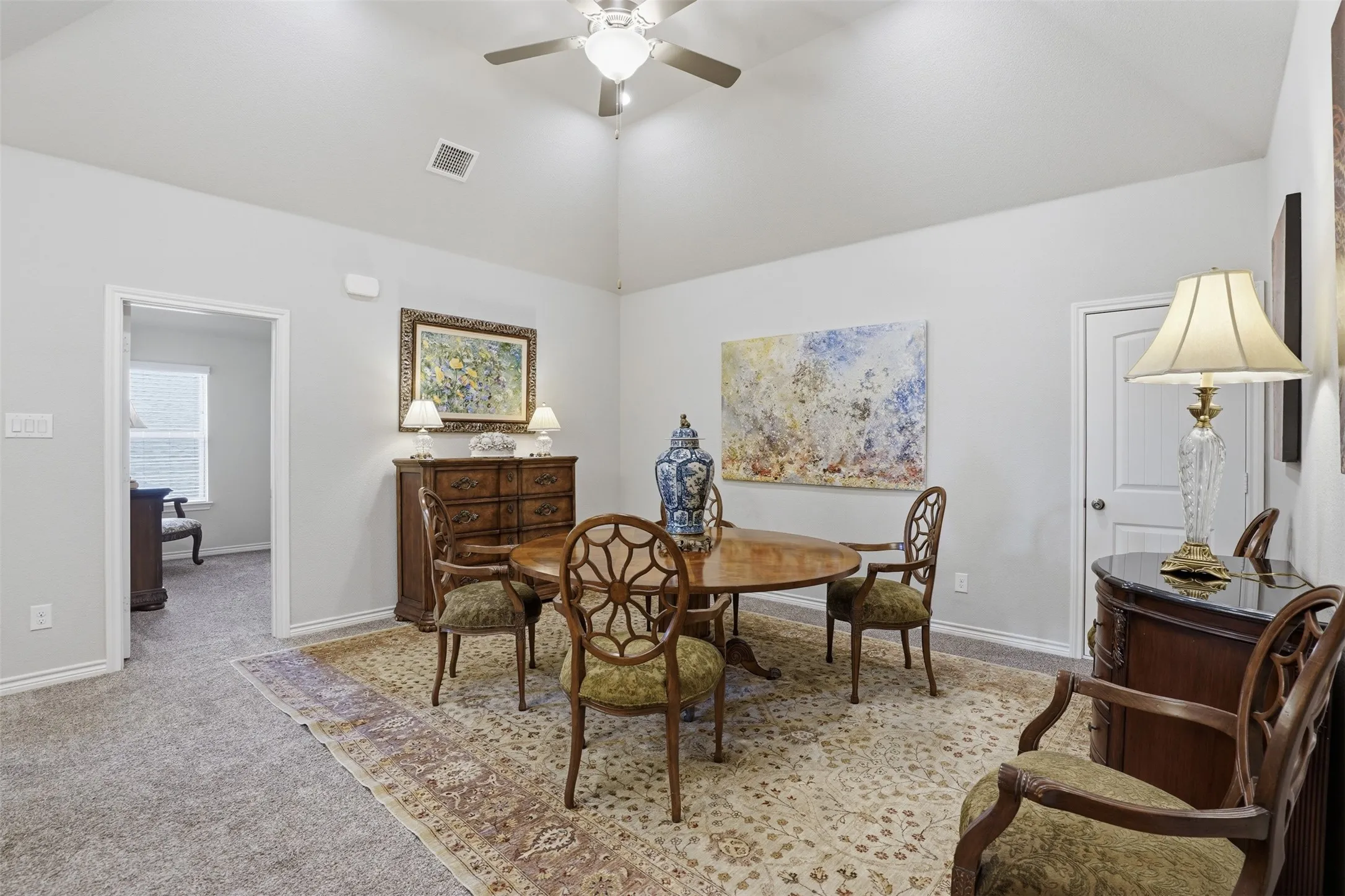 Vaulted ceiling with a ceiling fan, light gray wall paint, and gray carpeting