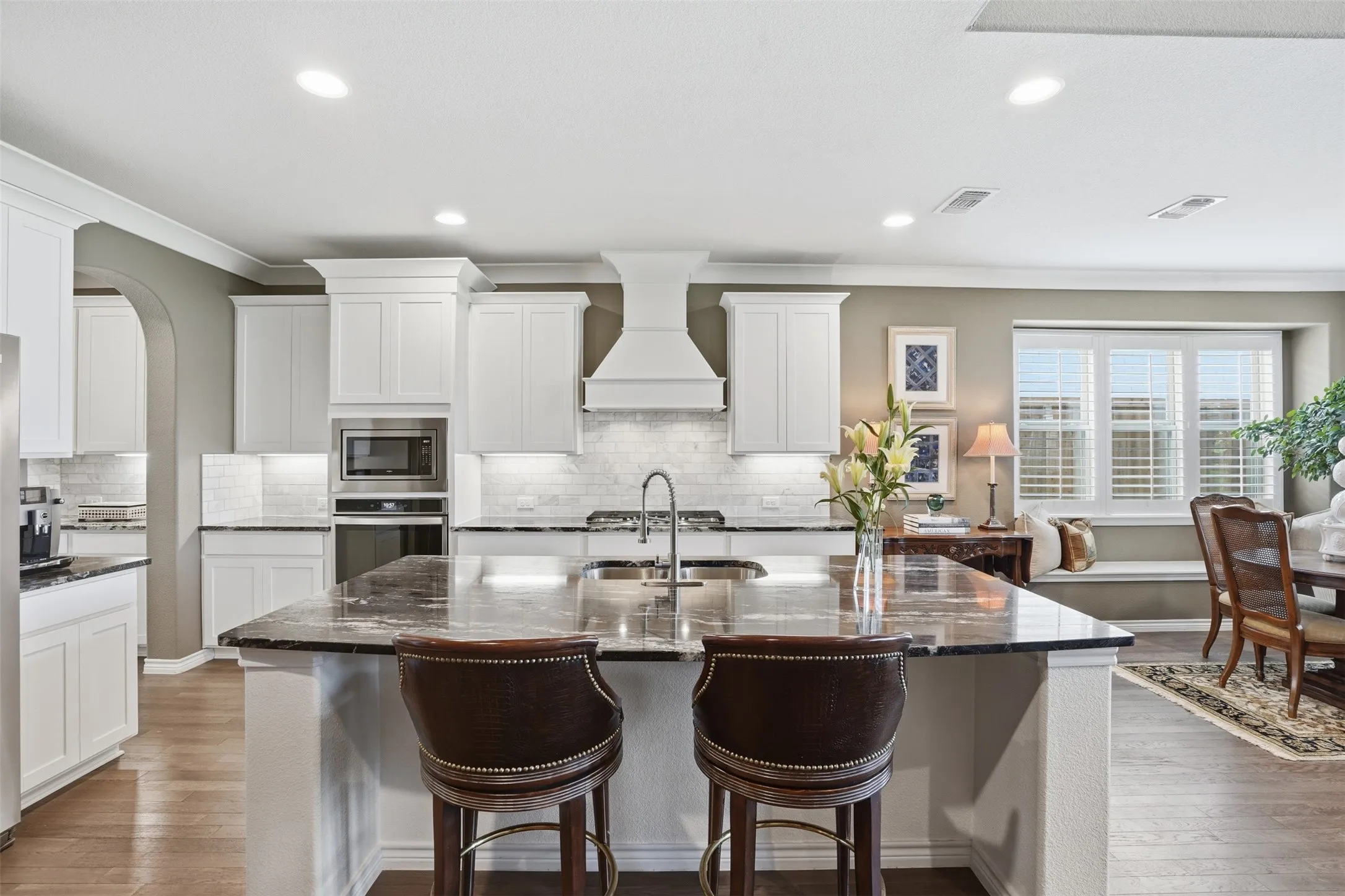 Central kitchen island with dark stone countertop and integrated sink
