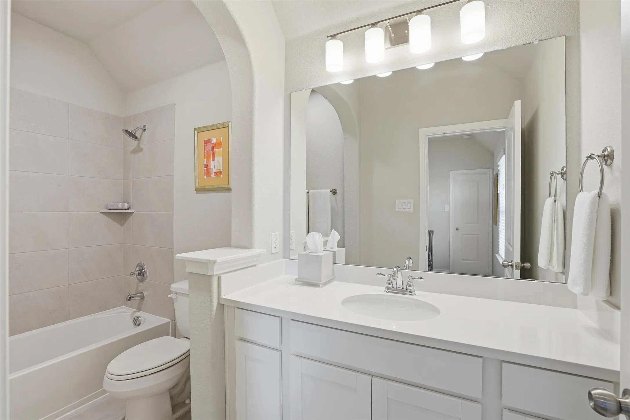 Bathroom featuring a single vanity with a white countertop, chrome fixtures, built-in cabinetry, and a shower-tub combination with tile surround