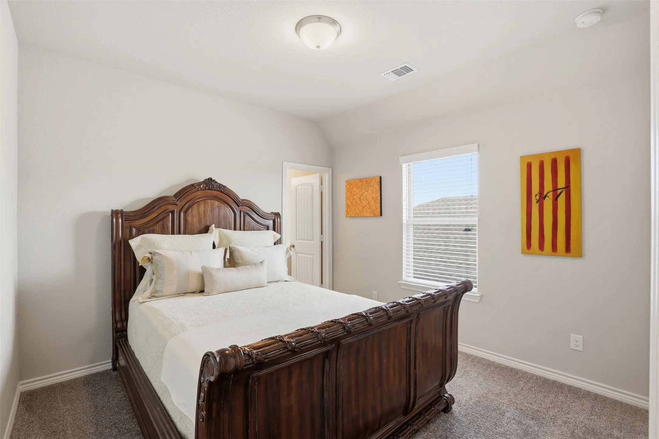 Carpeted bedroom featuring neutral wall tones, a ceiling-mounted light fixture, and a window with horizontal blinds