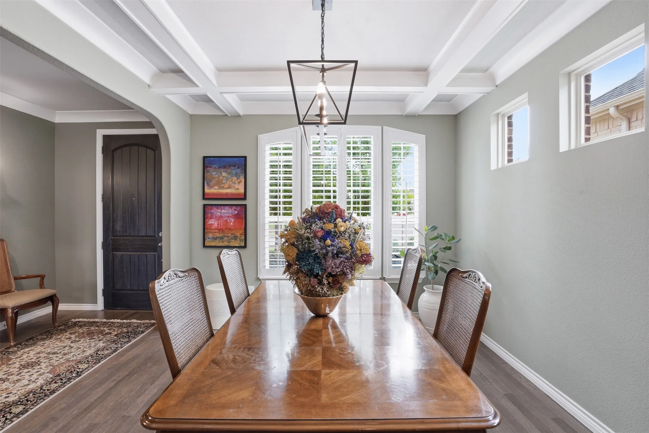 Dining area featuring a coffered ceiling, wood-finish flooring, and a contemporary chandelier
