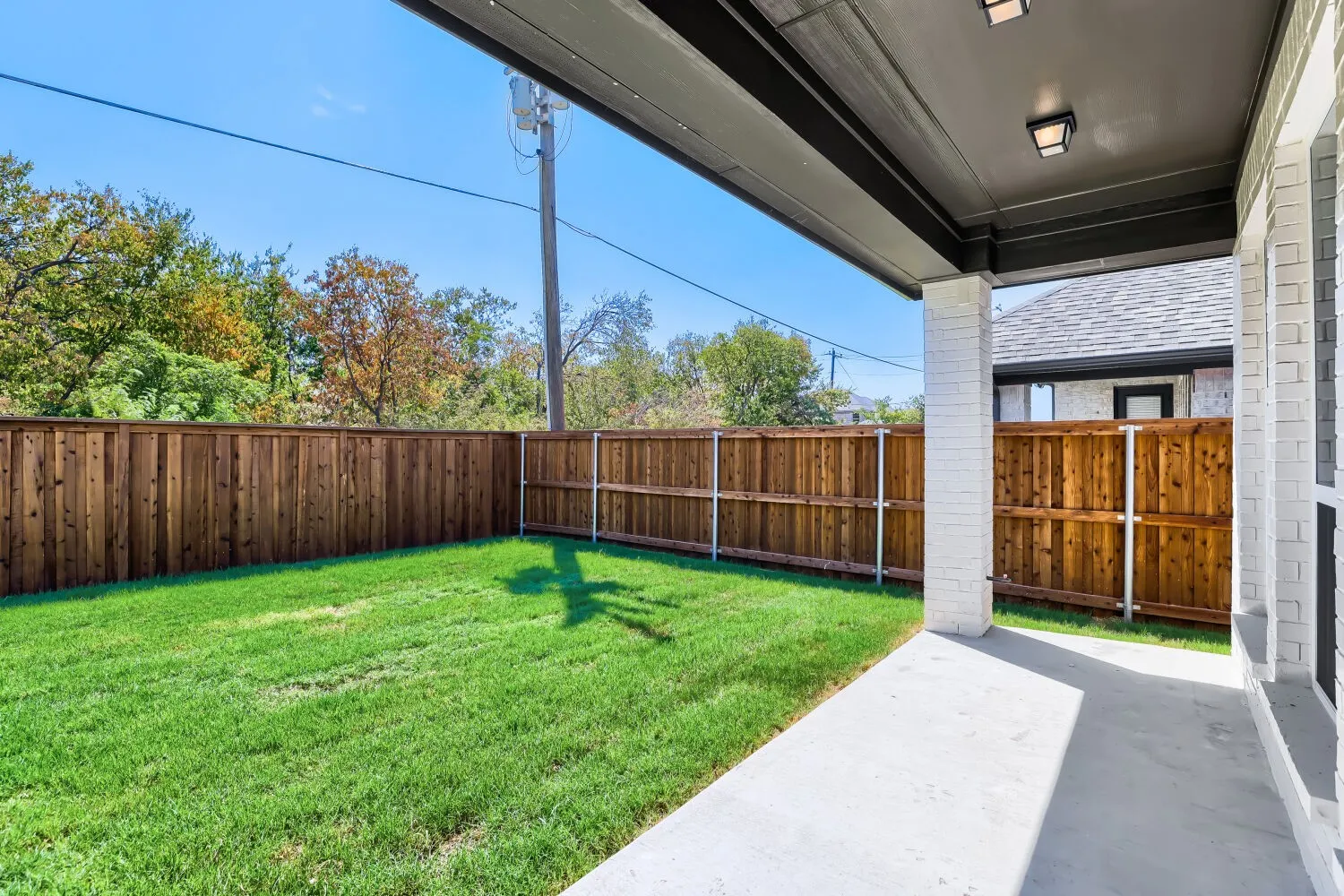 Covered patio area with a concrete surface, white brick column, and recessed lighting fixtures