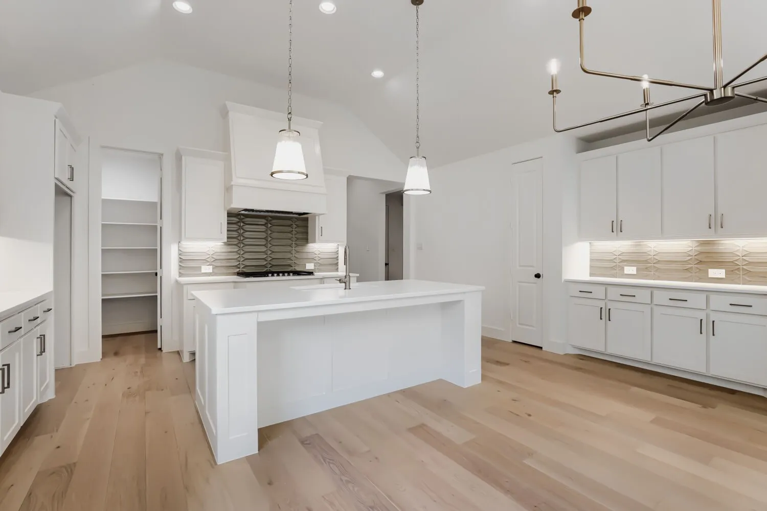 Kitchen featuring an island, white cabinetry, integrated range hood, tile backsplash, and light wood-finish flooring