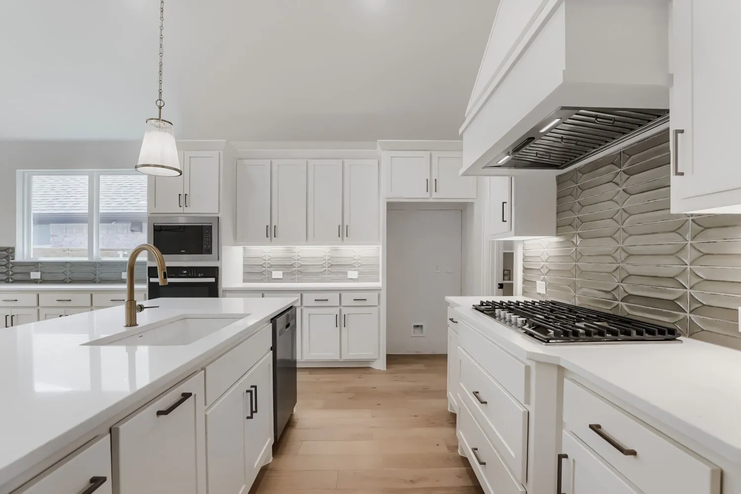 Gourmet kitchen featuring white shaker cabinetry, quartz countertops, a large island with waterfall edge, professional-grade gas cooktop with stainless steel hood, and a subway tile backsplash