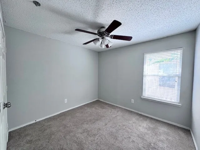 Carpeted room featuring light gray walls, a window with horizontal blinds, a ceiling fan with light fixture, and white trim