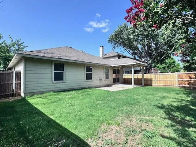 Spacious backyard featuring a covered patio, a new wood privacy fence, and a generous lawn area