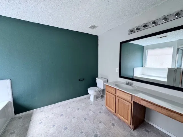 Bathroom featuring a wood-finish vanity with a single basin sink and extended countertop, large vanity mirror, and a linear light fixture