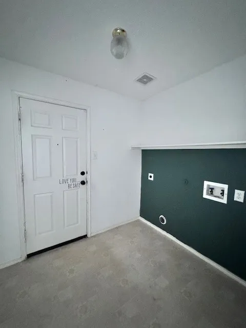 Laundry area featuring a multi-panel door, neutral flooring, and a dark accent wall