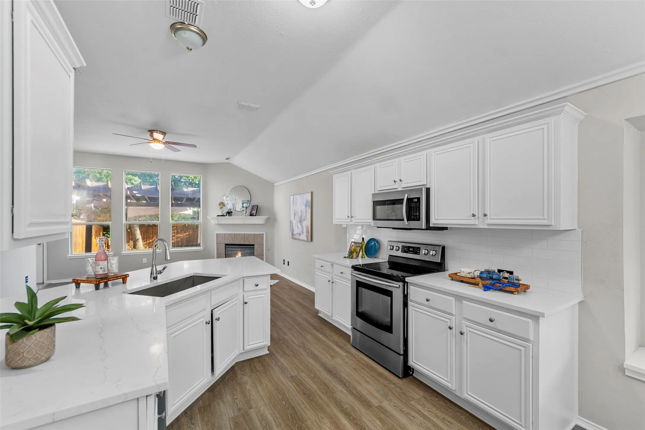 Beautifully updated kitchen featuring fresh paint, new flooring, bright white cabinetry, quartz countertops, stainless steel appliances, and a spacious breakfast bar perfect for casual dining and entertaining. The open-concept design flows seamlessly into the breakfast area and living space, creating an airy and inviting atmosphere. Vaulted ceilings and abundant natural light enhance the sense of space, while the functional layout offers both style and everyday convenience. The adjacent dining area provides the perfect setting for family meals, morning coffee, or intimate gatherings.