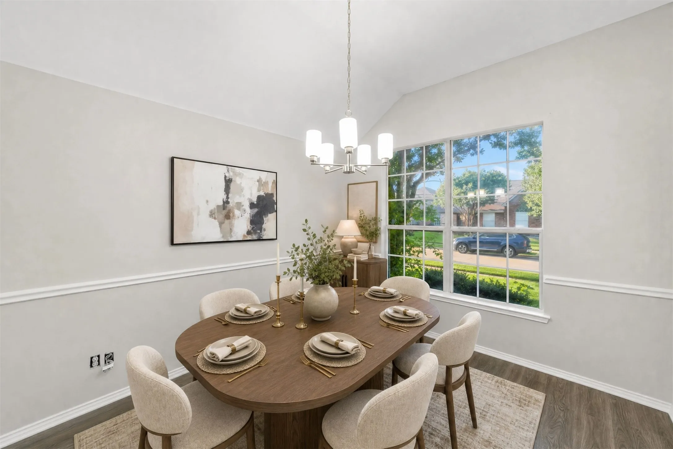 The spacious formal dining room offers vaulted ceilings, abundant natural light, fresh paint, new wood-look plank flooring, and an updated chandelier. A large picture window overlooks the mature trees in the front yard, creating an elegant setting for both everyday dining and special occasions. Virtual staged