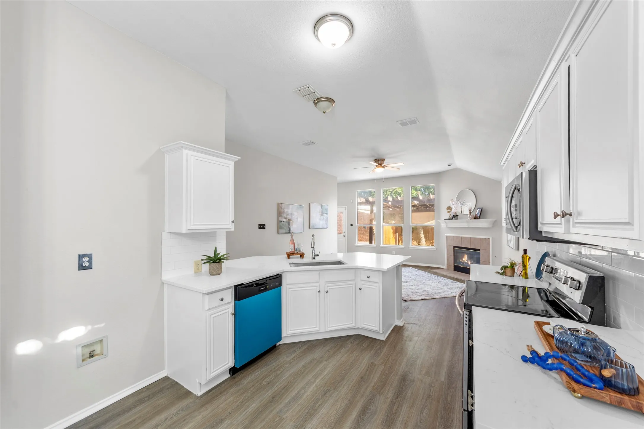 Beautifully updated kitchen featuring fresh paint, new flooring, bright white cabinetry, quartz countertops, stainless steel appliances, and a spacious breakfast bar perfect for casual dining and entertaining. The open-concept design flows seamlessly into the breakfast area and living space, creating an airy and inviting atmosphere. Vaulted ceilings and abundant natural light enhance the sense of space, while the functional layout offers both style and everyday convenience. The adjacent dining area provides the perfect setting for family meals, morning coffee, or intimate gatherings.