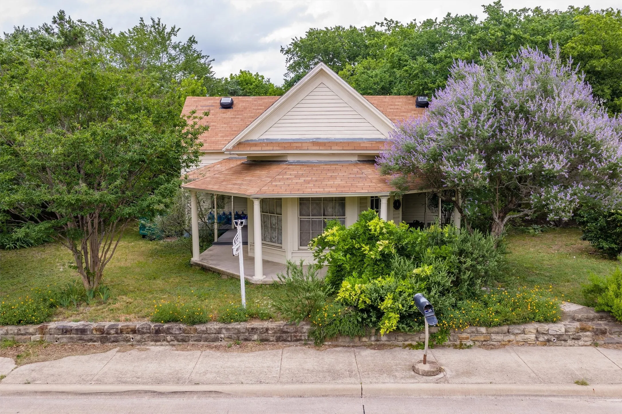 Gable-front home featuring a covered wraparound porch, horizontal siding, and a gabled roof