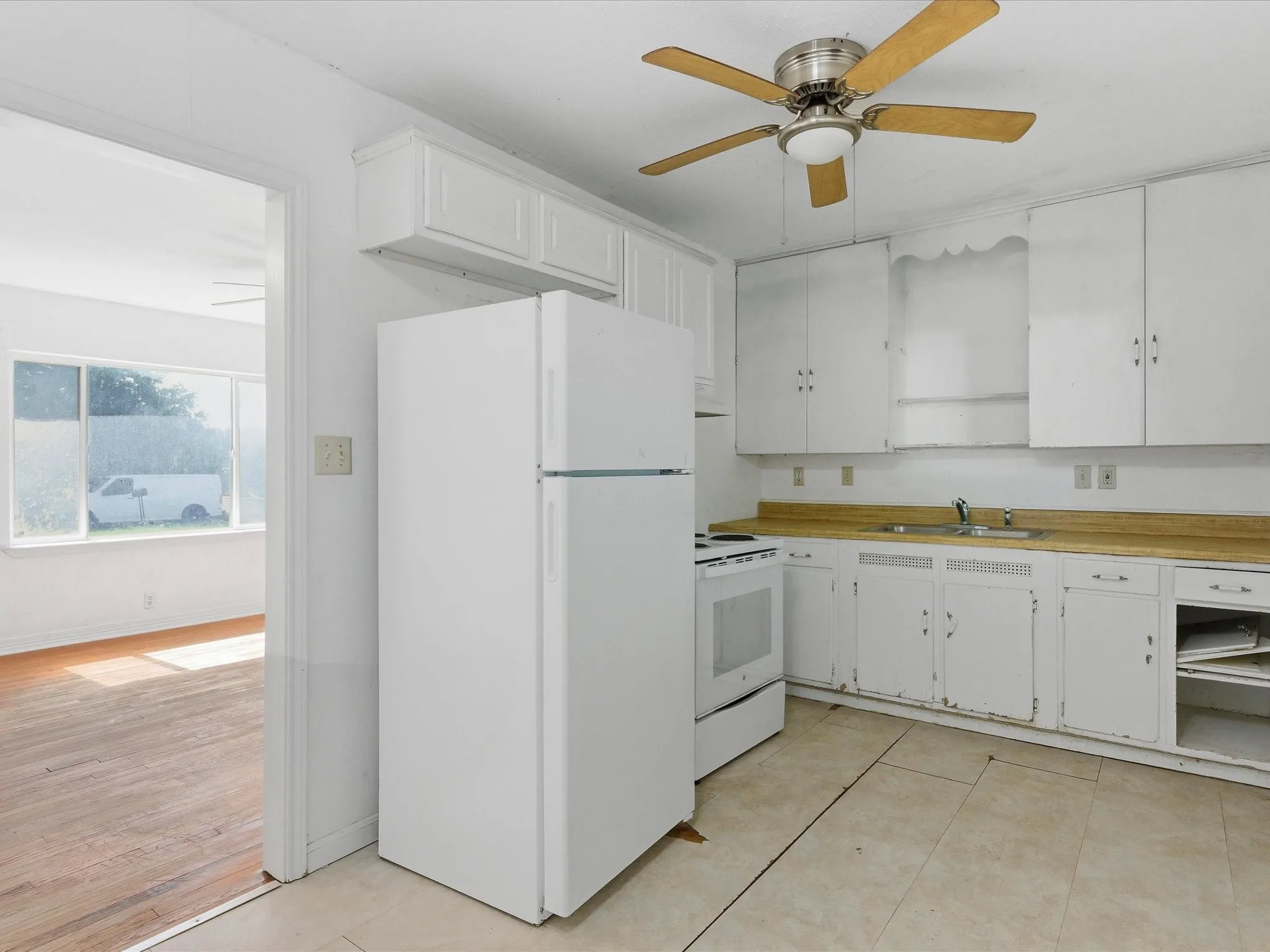 Kitchen featuring white appliances, a ceiling fan with light fixture, and extensive cabinetry