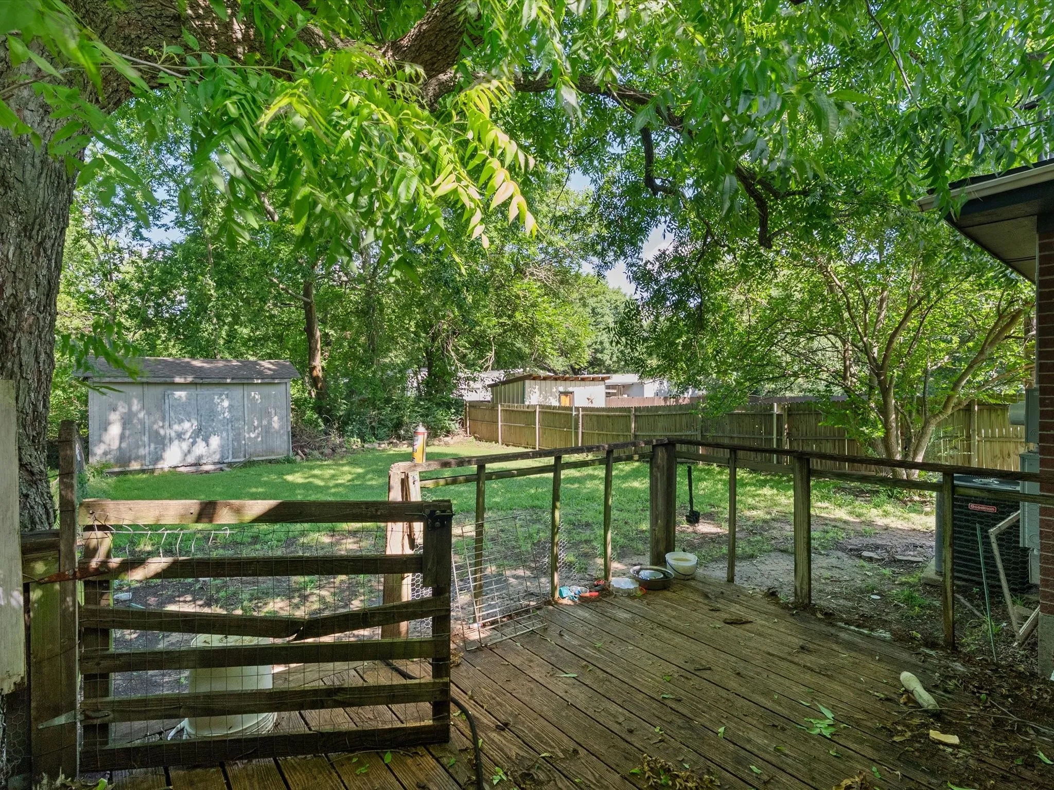 Expansive backyard featuring a wood deck, wood gate, and a storage shed