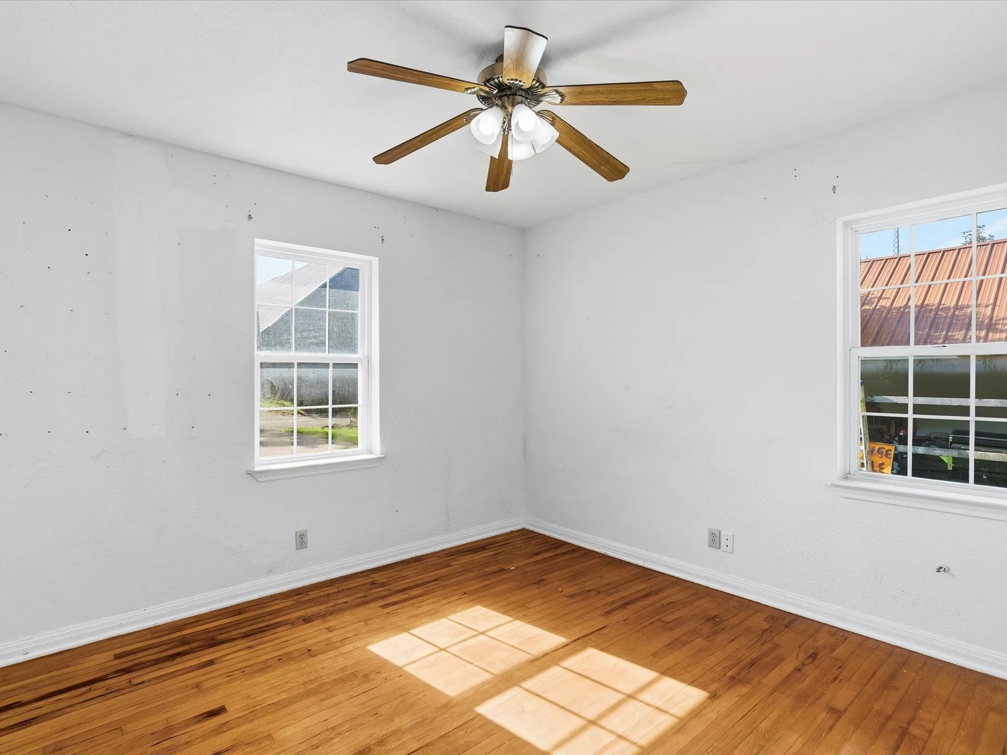 Room featuring wood-finish flooring, white walls, and a ceiling fan with integrated lighting