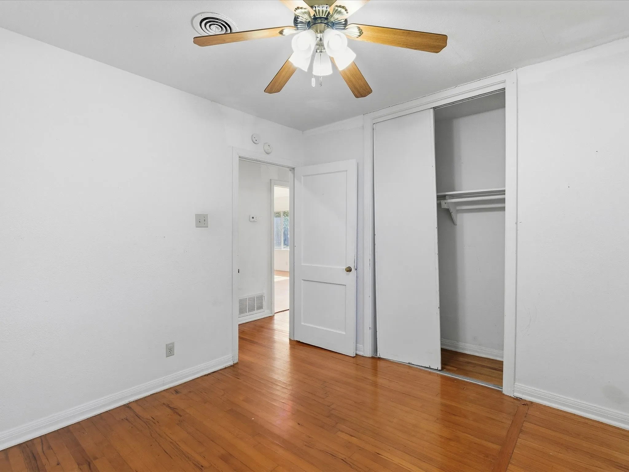 Room featuring wood-finish flooring, white baseboards, and a ceiling fan with integrated lighting
