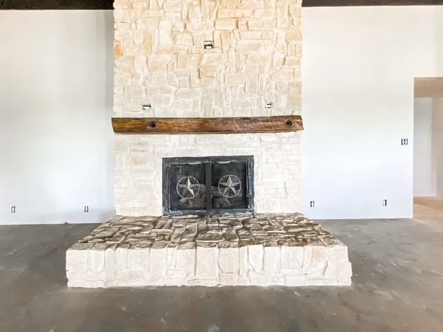 stone wood burning fireplace with stained white oak mantle