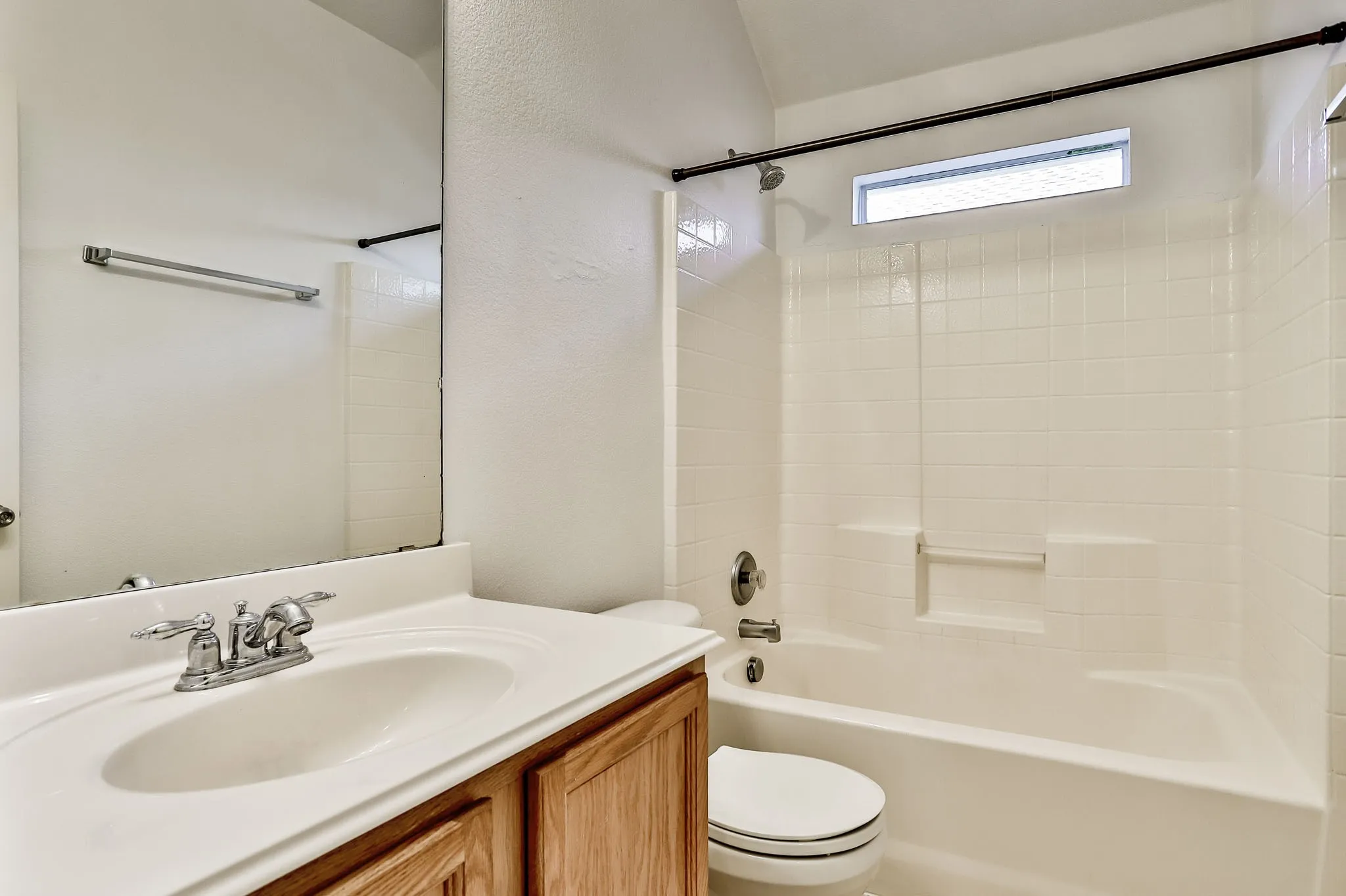 Bathroom featuring a single vanity with a white integrated sink, chrome faucet, and wood-finish cabinetry