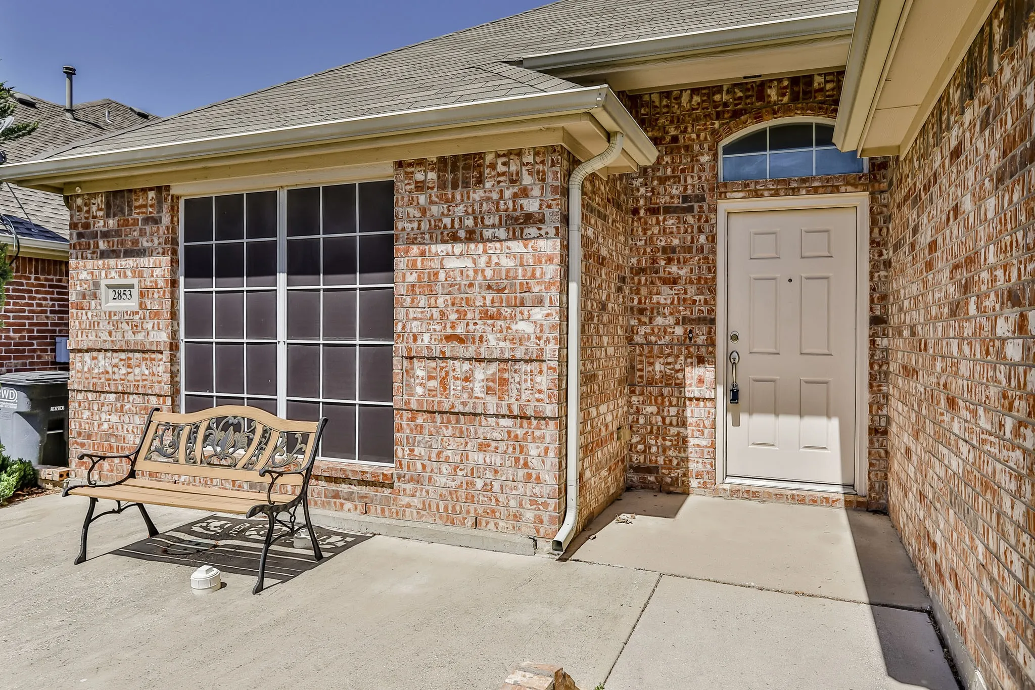 Brick exterior with a peaked roofline, front entry door, and an arched transom window