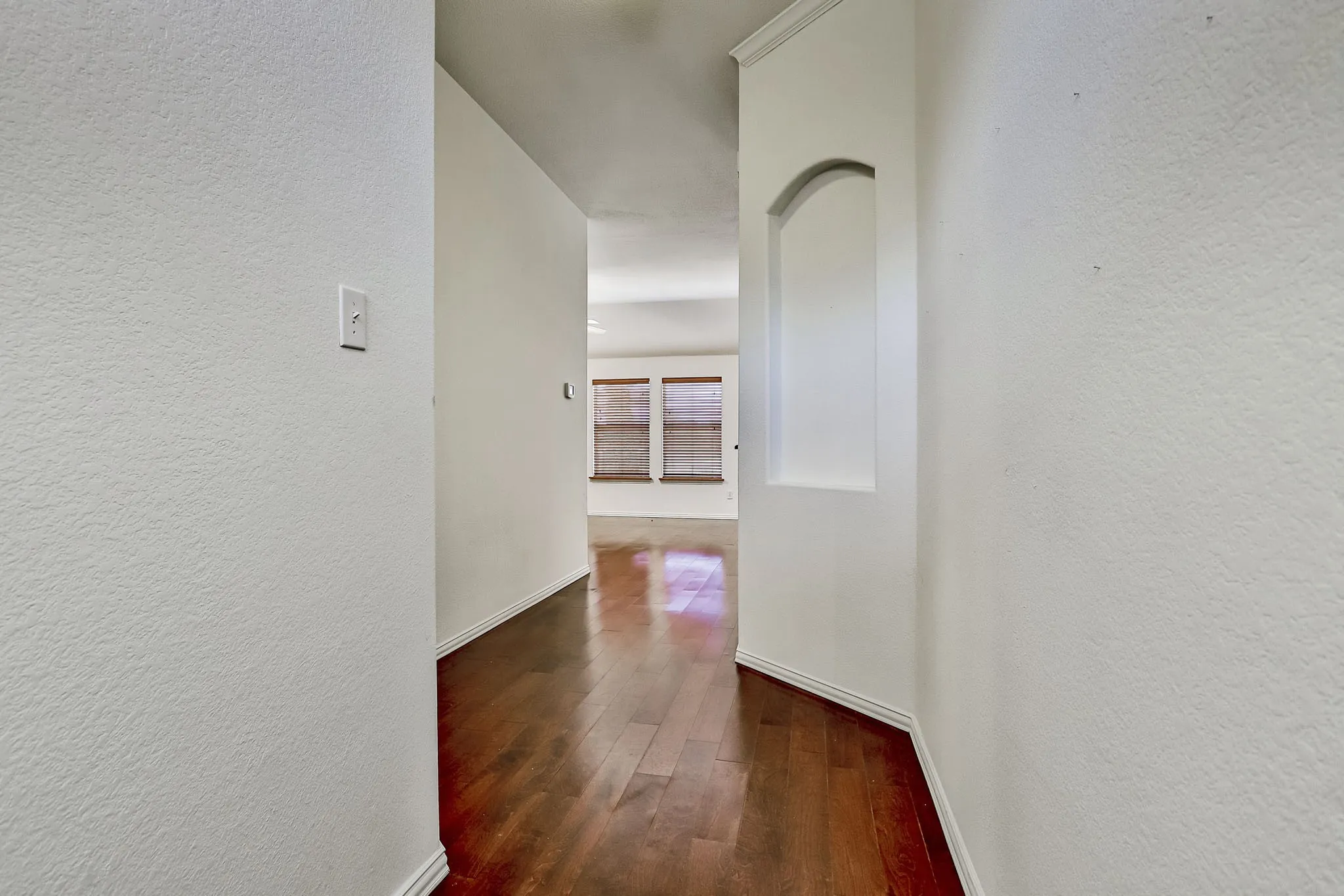 Hallway with wood-finish flooring and a built-in arched alcove