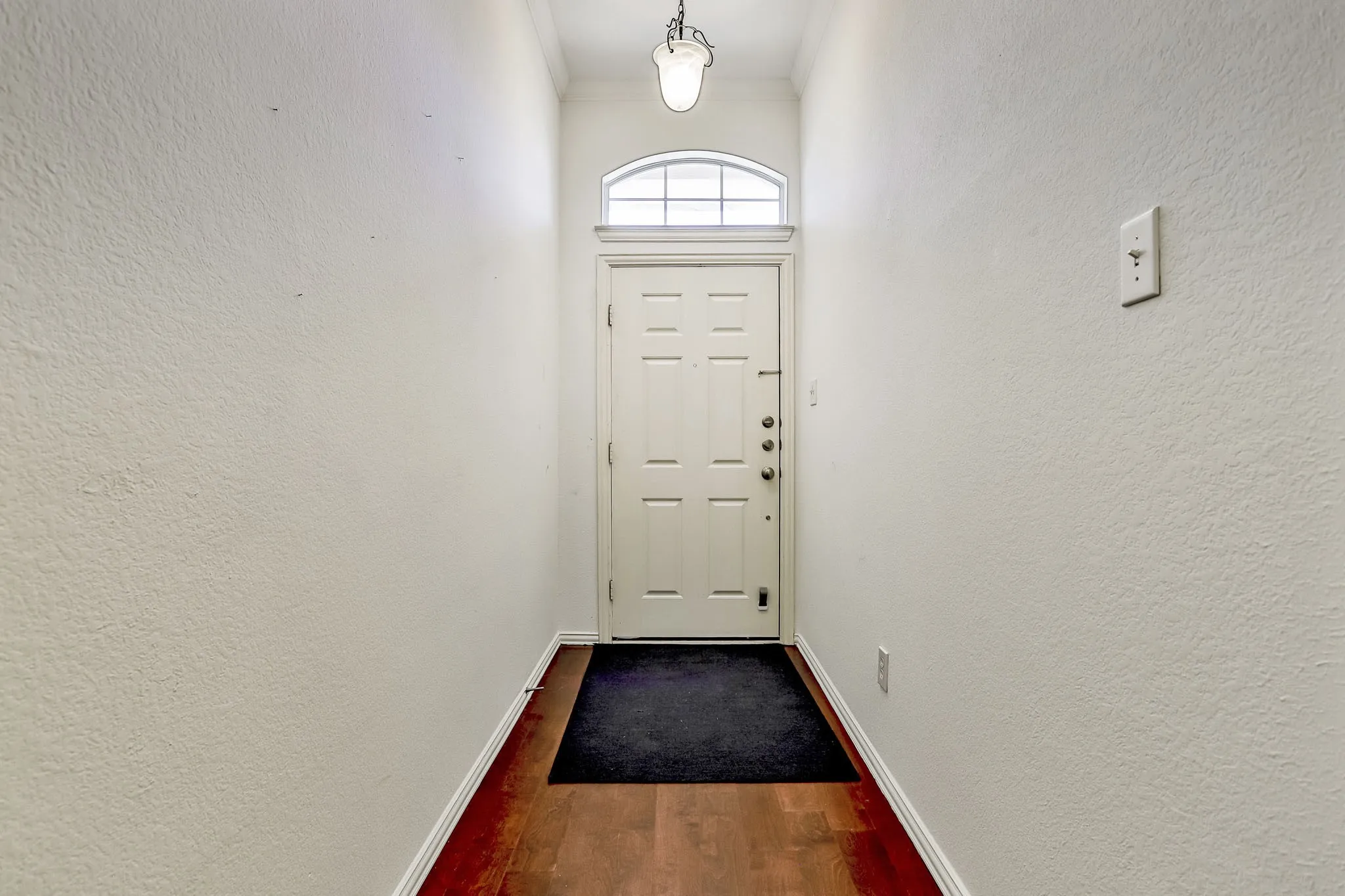 Entryway featuring wood-finish flooring and a paneled door with an arched transom window