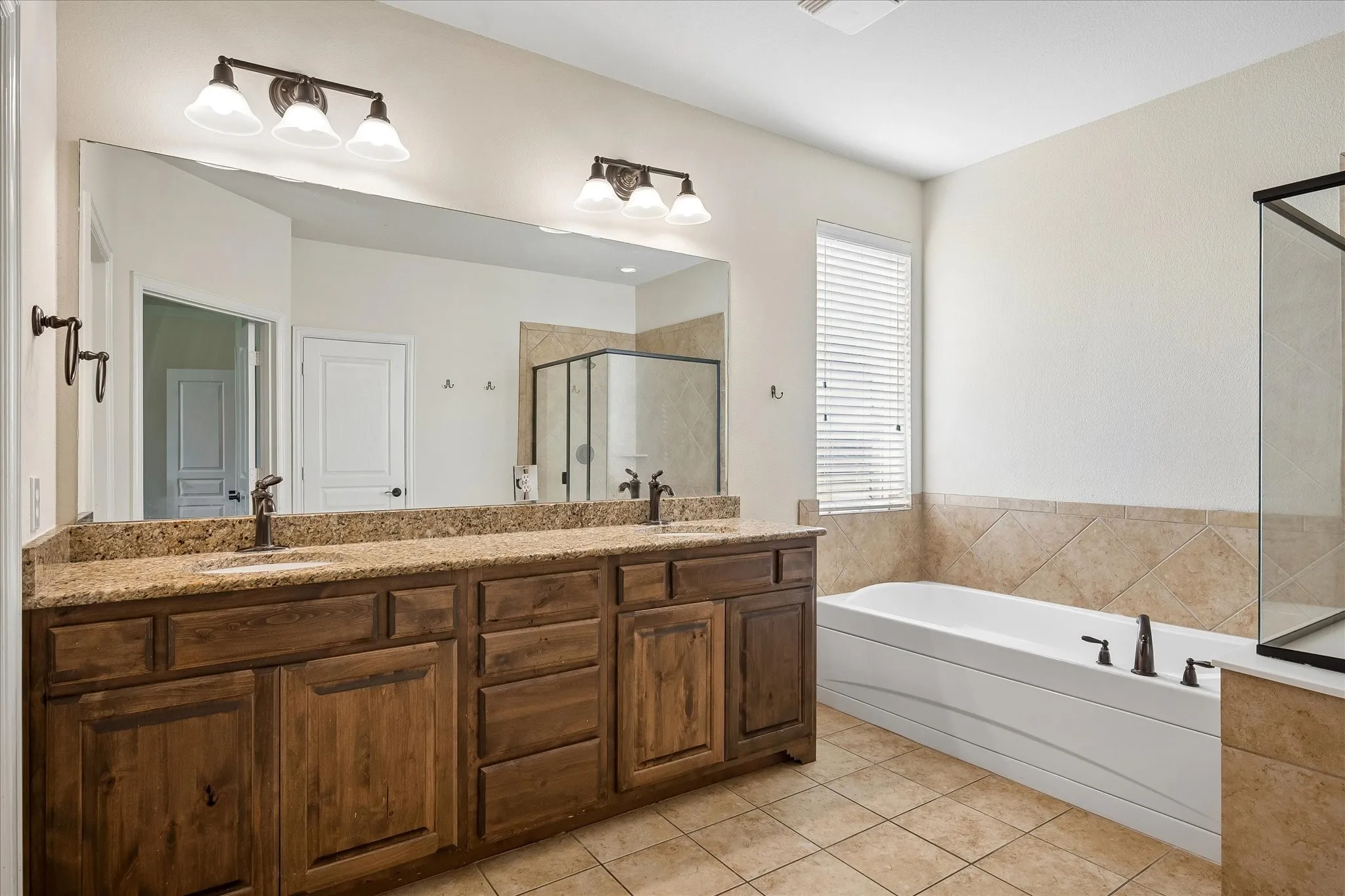 Dual vanity with granite countertop, wood-finish cabinetry, and bronze-finish fixtures