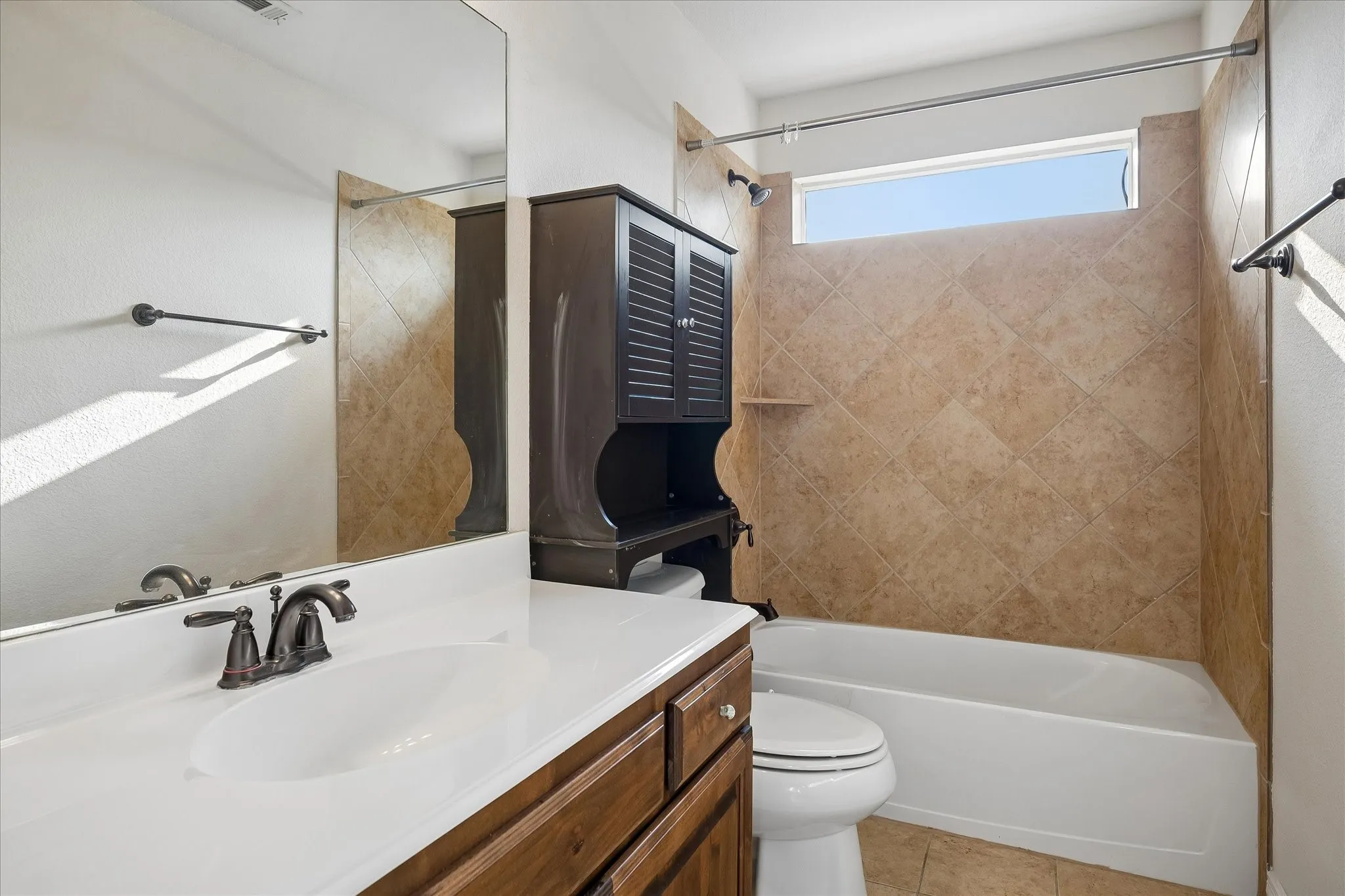 Vanity with a white countertop and integrated sink, bronze-finish faucet, and wood-finish cabinetry