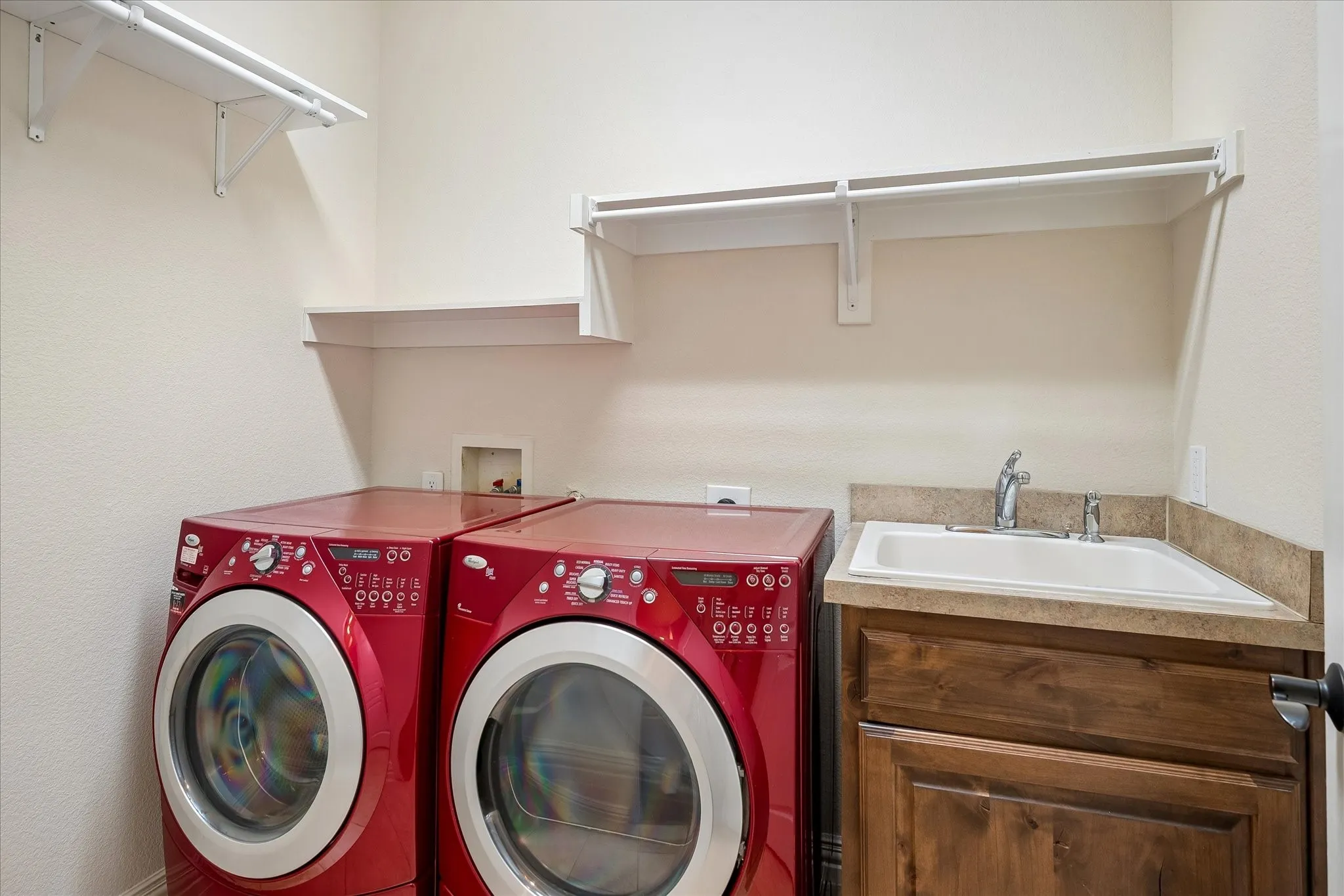 Built-in cabinetry with a basin sink, wall-mounted shelving, and hanging rods