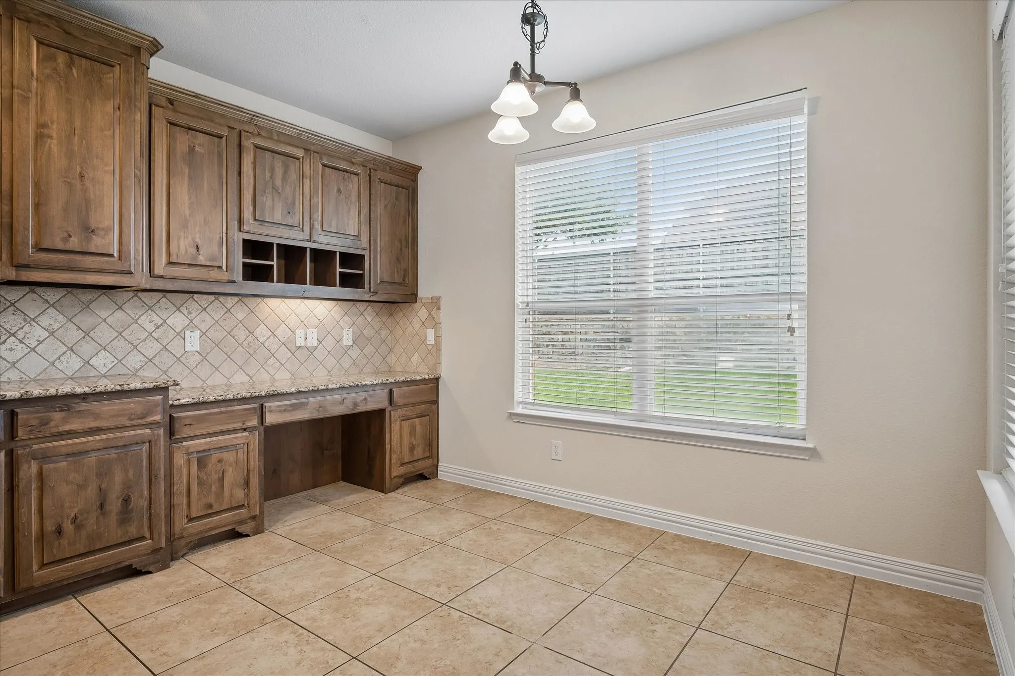 Built-in wood cabinetry with integrated desk space, granite countertops, and a full-height tile backsplash