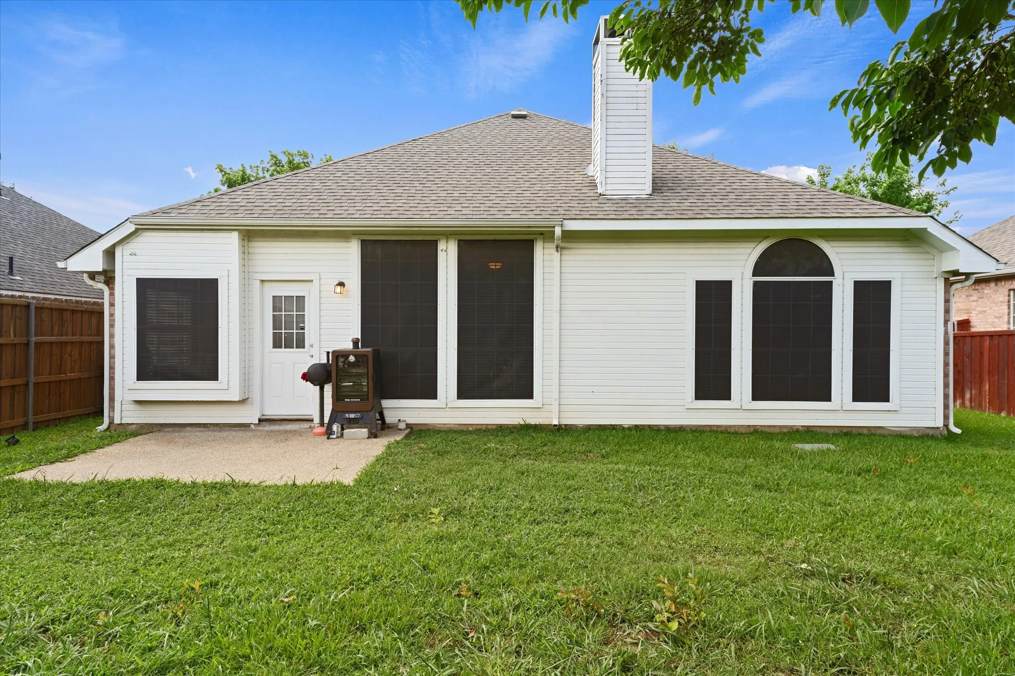 Rear elevation showcases the home's large windows, covered patio, and attractive architectural details. The layout allows natural light to flow throughout the interior living spaces.