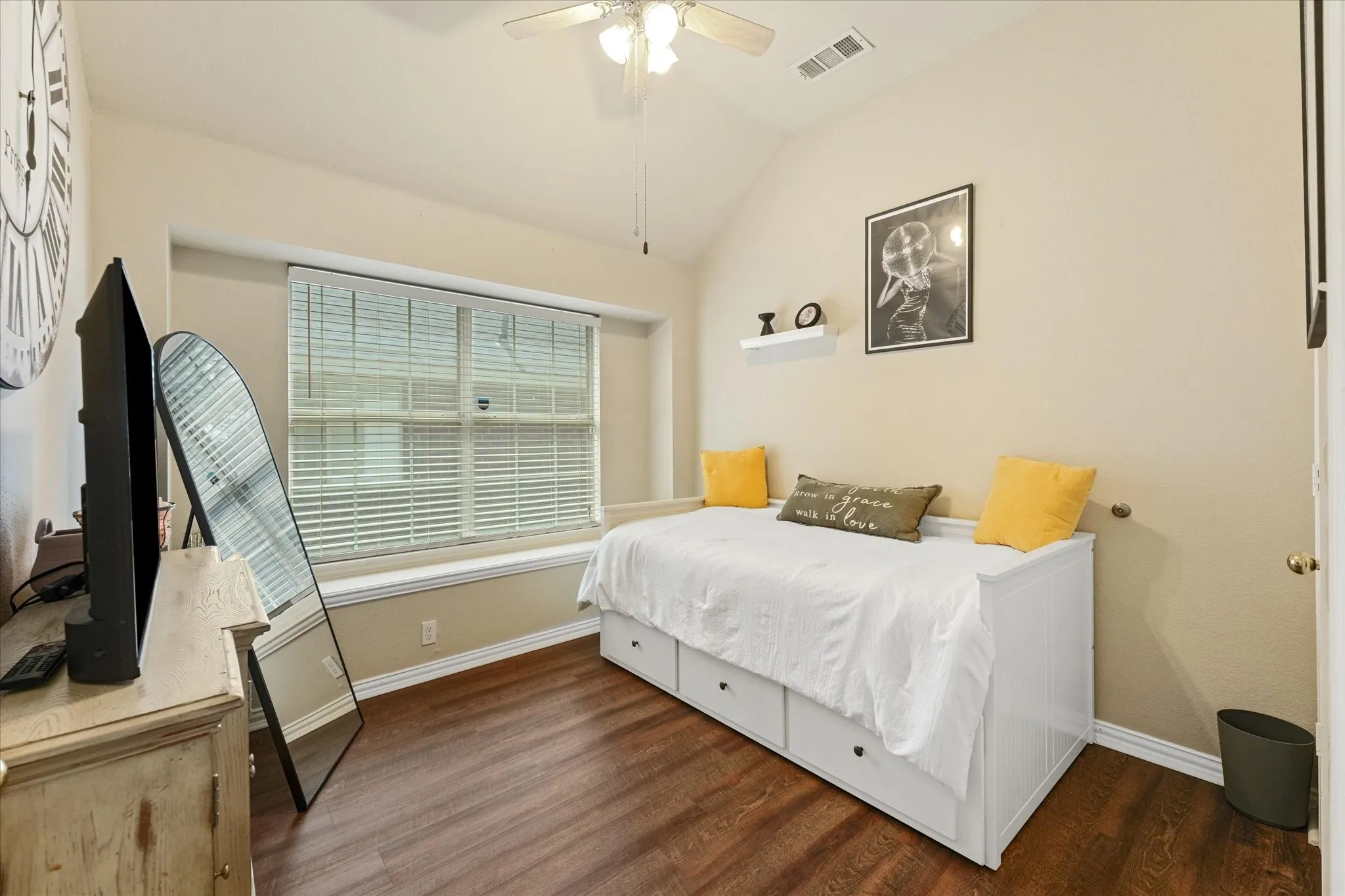Bright secondary bedroom featuring vaulted ceilings, luxury vinyl plank flooring, and a large window that brings in natural light. A flexible space that works well as a bedroom, guest room, hobby room, or home office.
