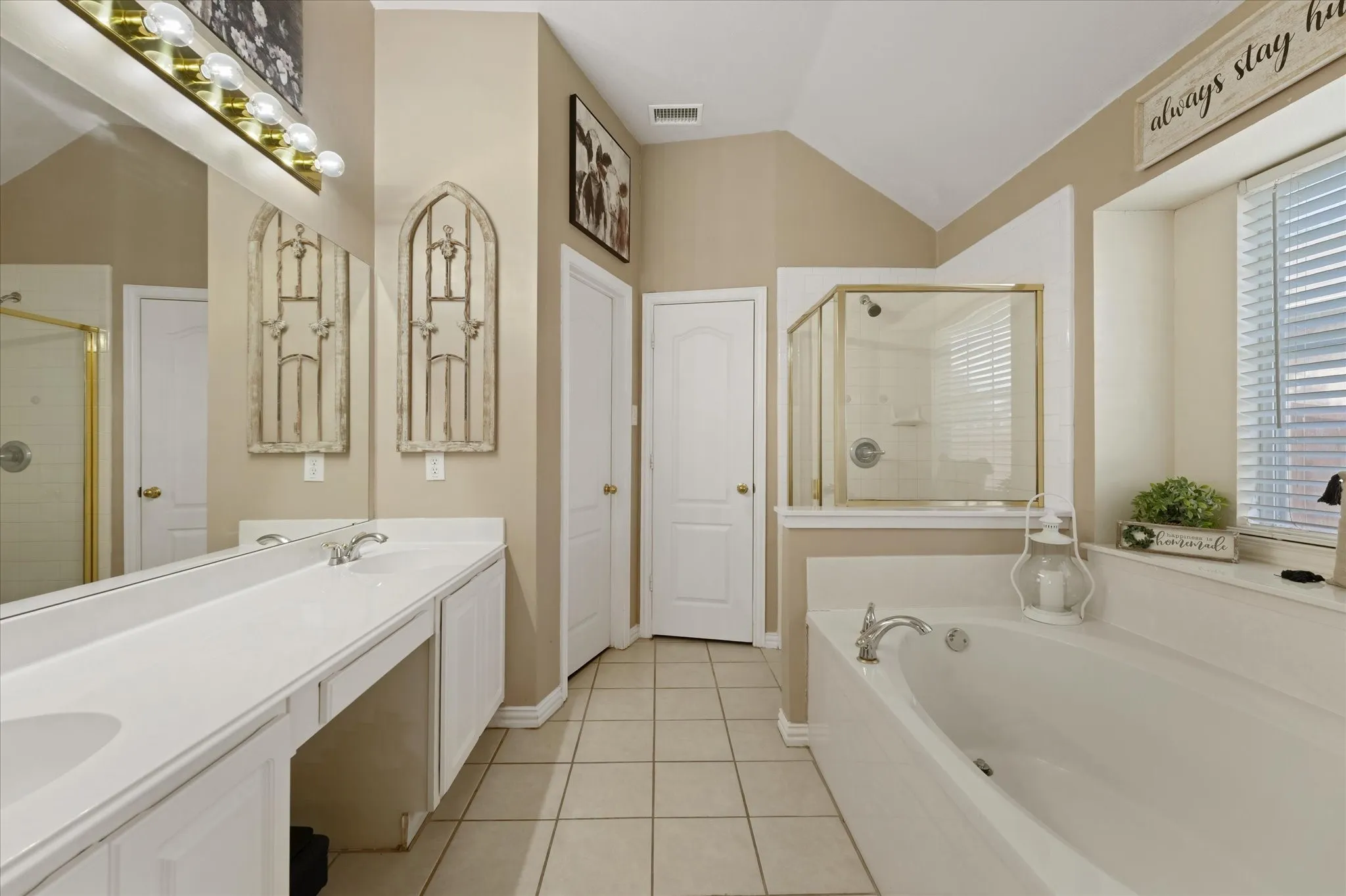 Large primary bathroom featuring dual vanities, a soaking tub, separate shower, and abundant natural light. The spacious layout offers excellent storage and room to personalize over time.