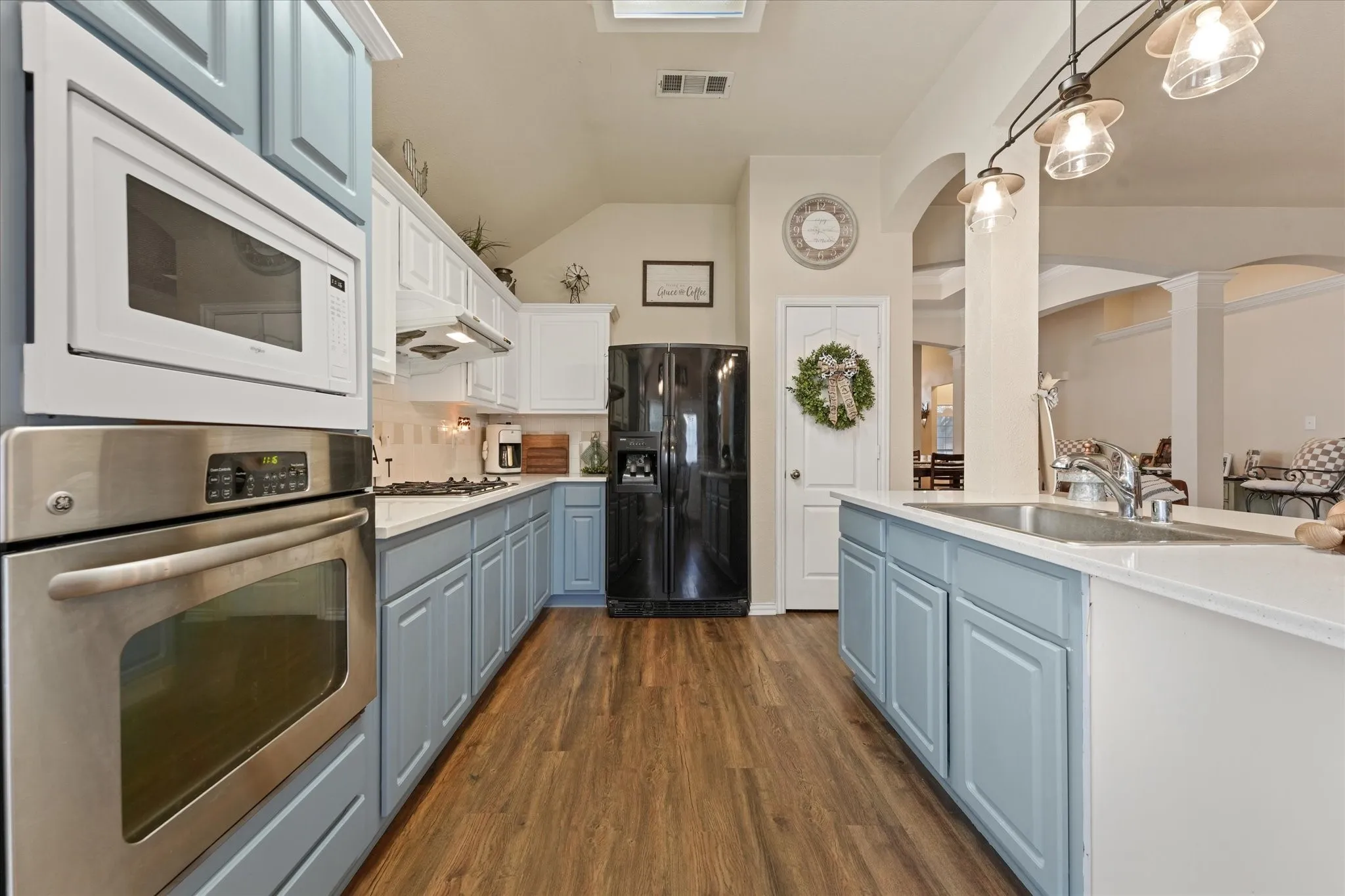 Well-appointed kitchen featuring painted cabinetry, double ovens, gas cooktop, abundant counter space, and a functional island with additional storage. The open layout keeps the kitchen connected to the living and dining areas, making everyday living and entertaining easy.