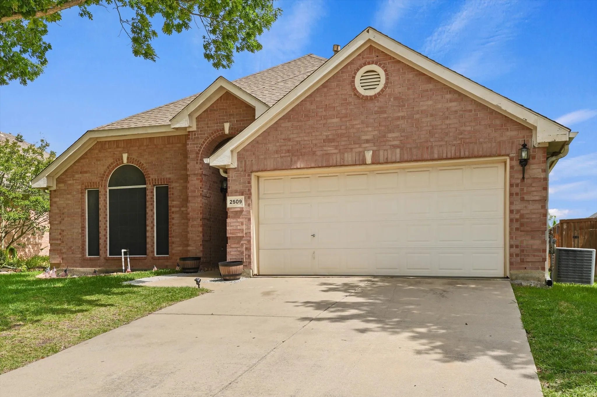 Single-story brick home with a two-car garage located in Wind River Estates. The spacious driveway, mature shade trees, and established neighborhood setting offer both convenience and curb appeal.
