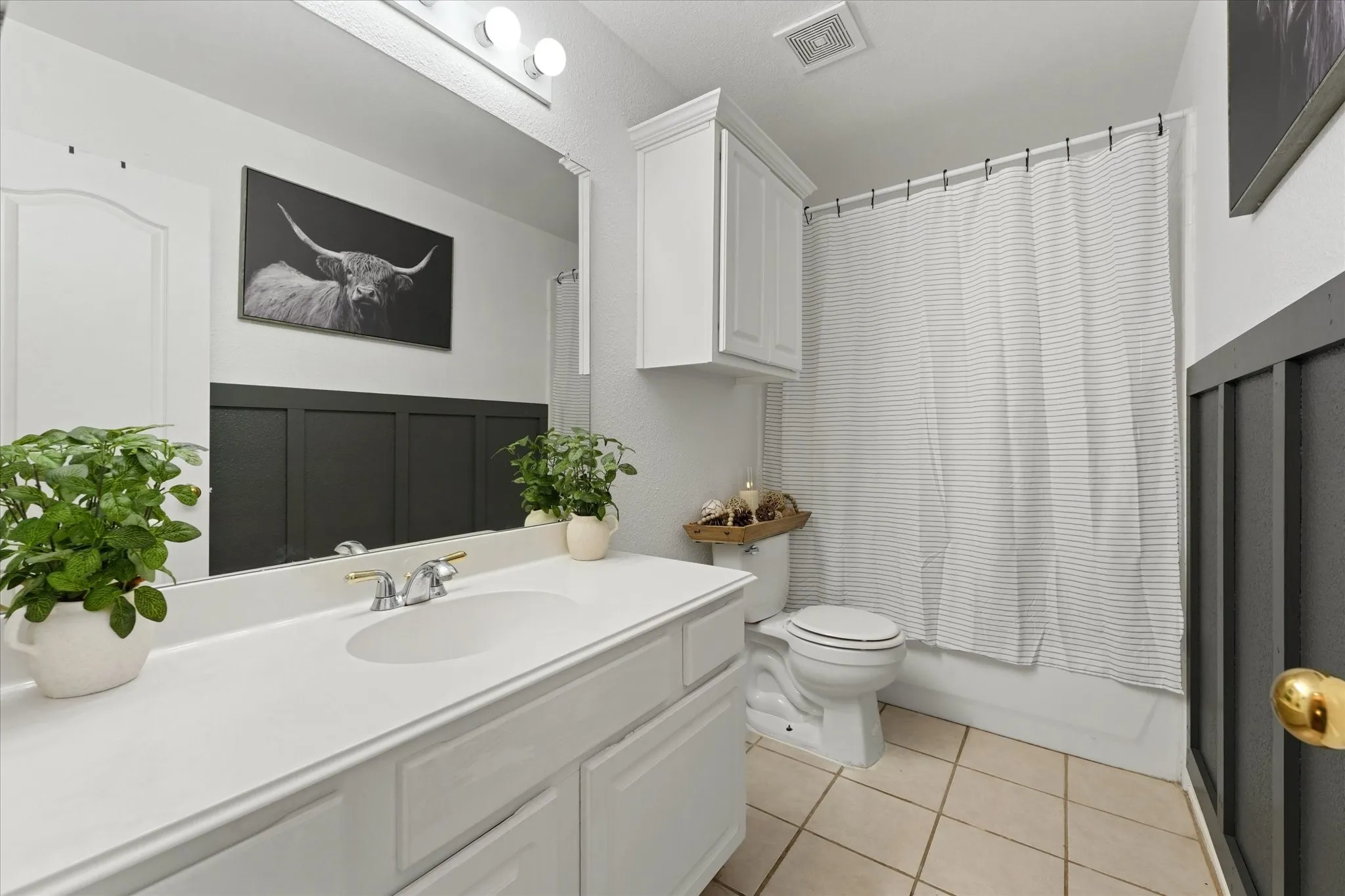 Updated guest bathroom featuring modern paint colors, decorative accent wall details, ample vanity space, and a full tub-shower combination. Conveniently located near secondary bedrooms.