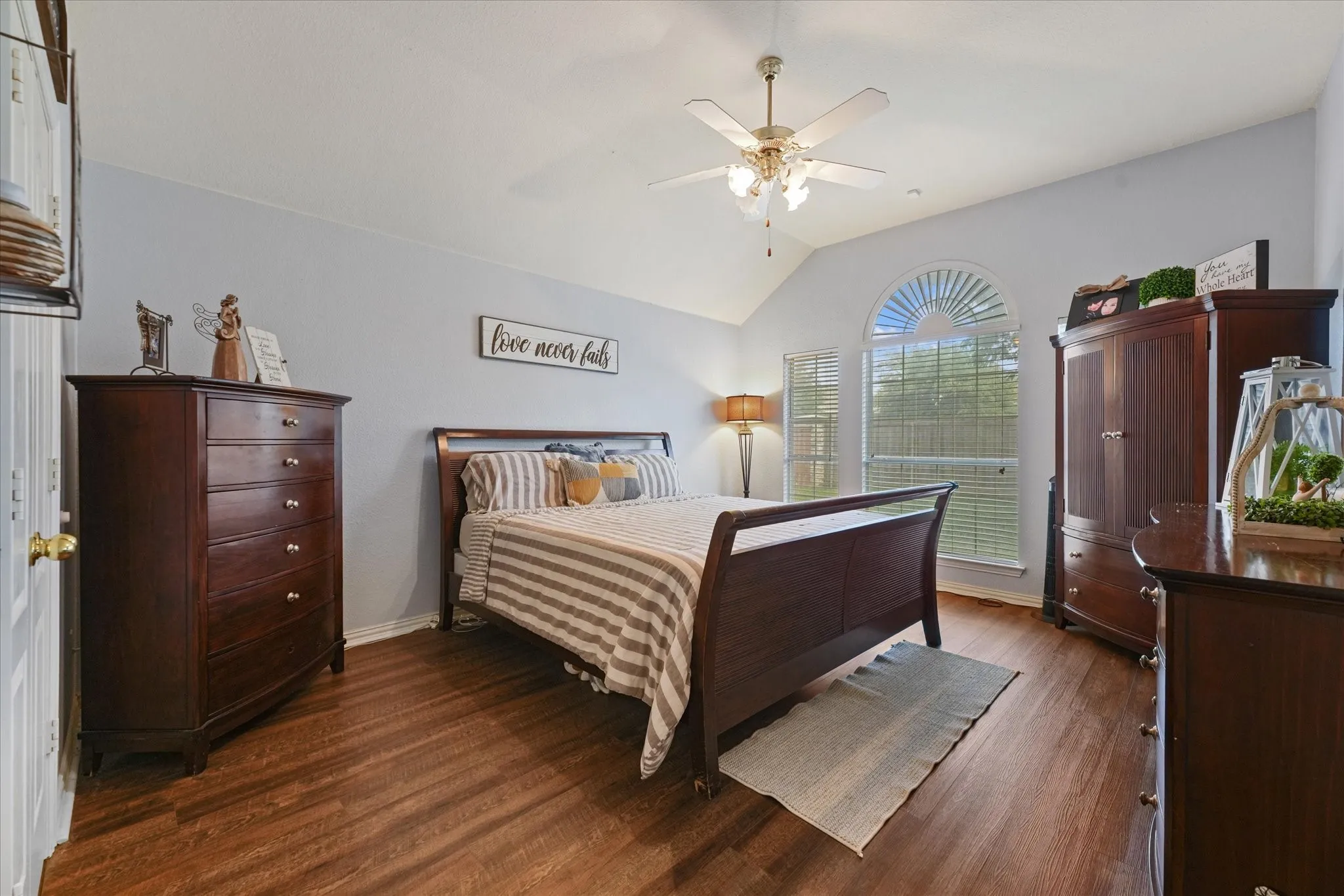Spacious primary suite featuring vaulted ceilings, updated flooring, and oversized windows that fill the room with natural light. The generous layout easily accommodates large furniture while maintaining an open, relaxing feel.