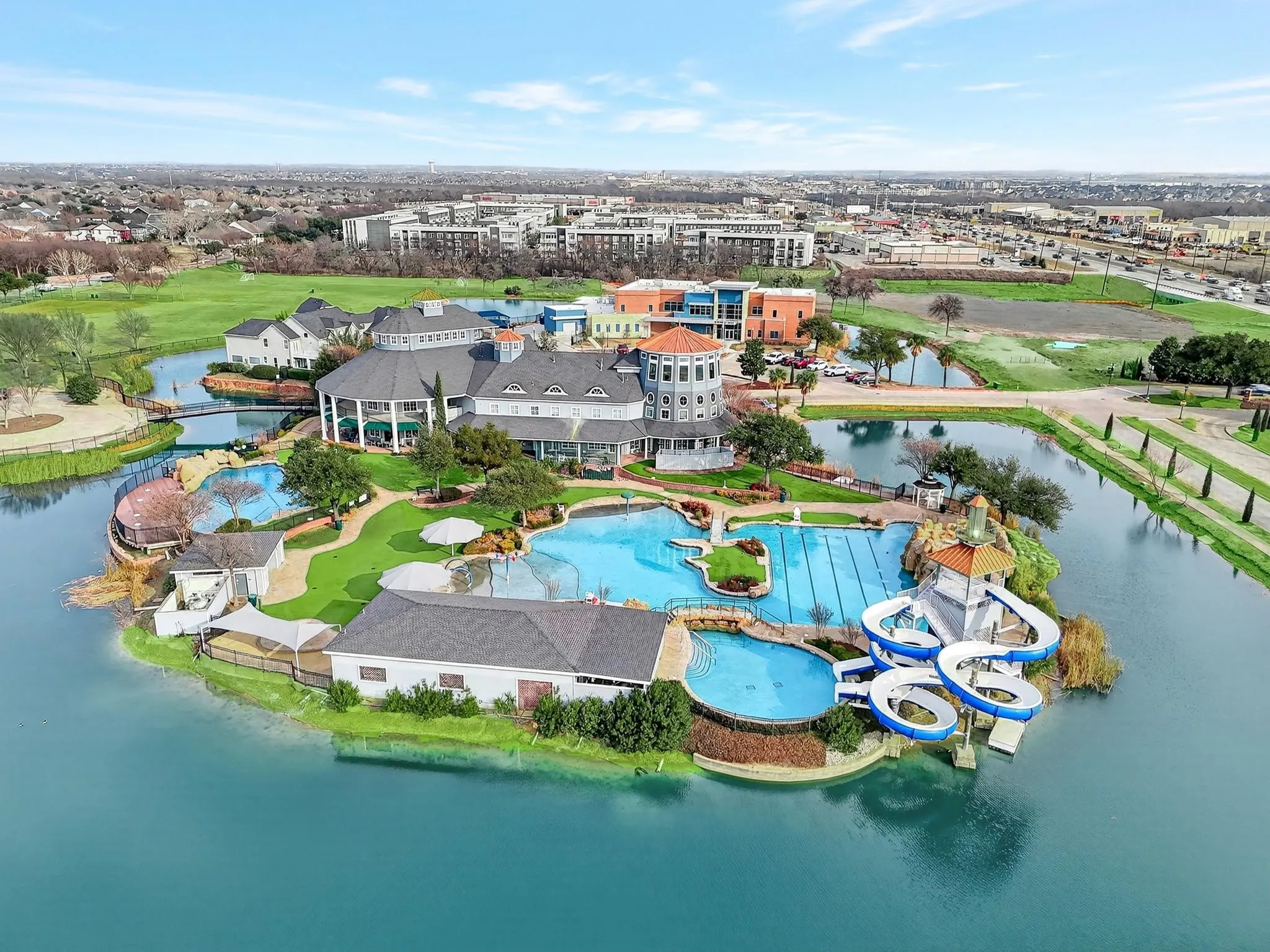 Expansive aquatic facility featuring multiple swimming pools, a water slide complex, and a central clubhouse with a distinctive turret
