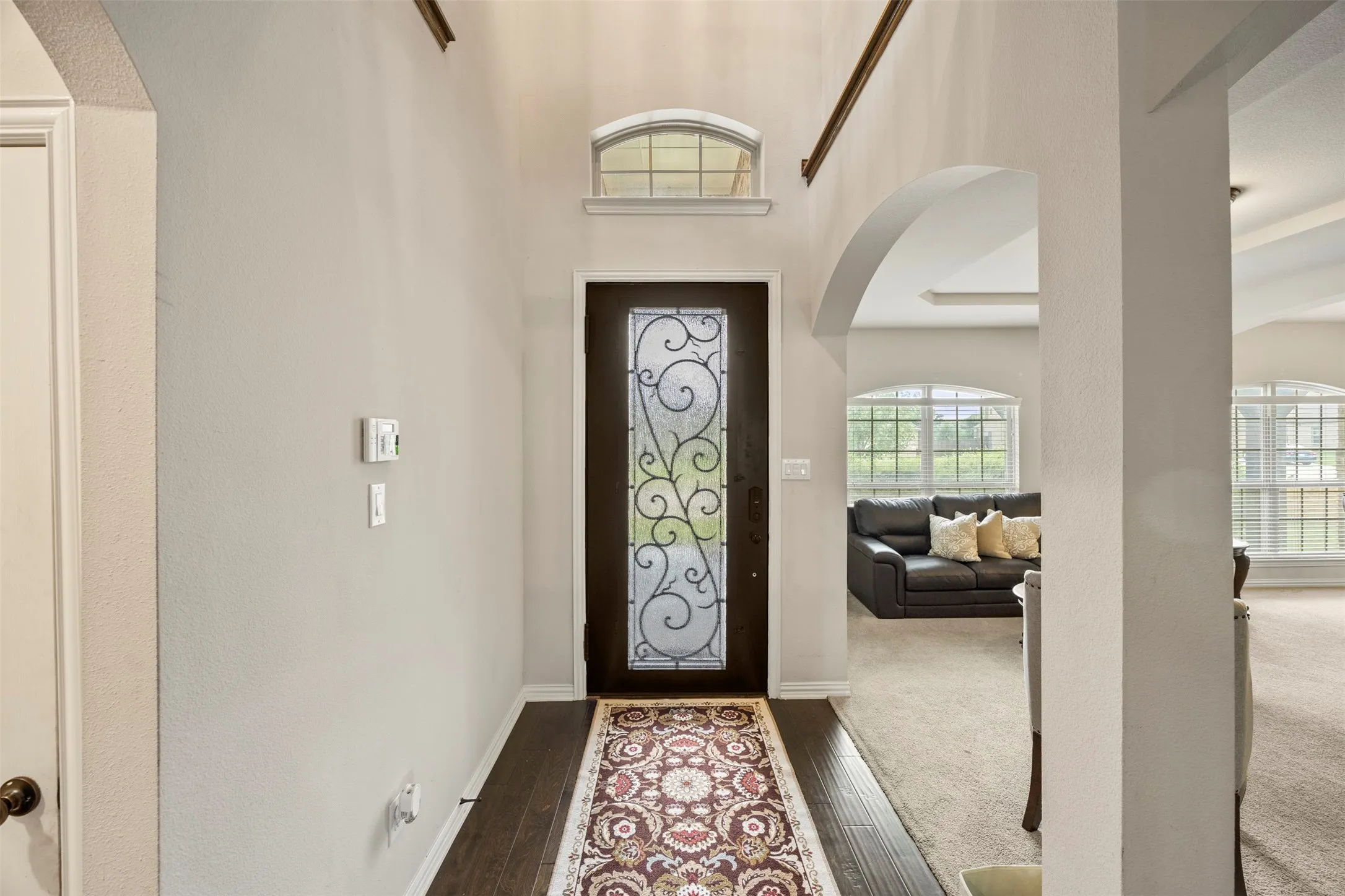 Entryway with dark wood-finish door and decorative glass, with the living room and dining to the left upon entry