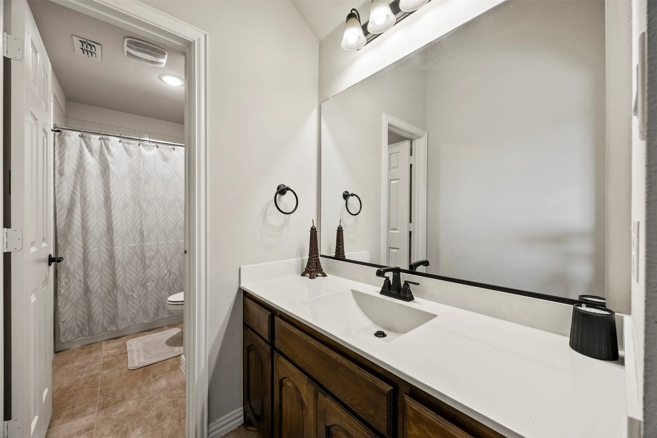 Contemporary bathroom featuring a wood-finish vanity with a light-toned countertop, an undermount sink, and a black faucet