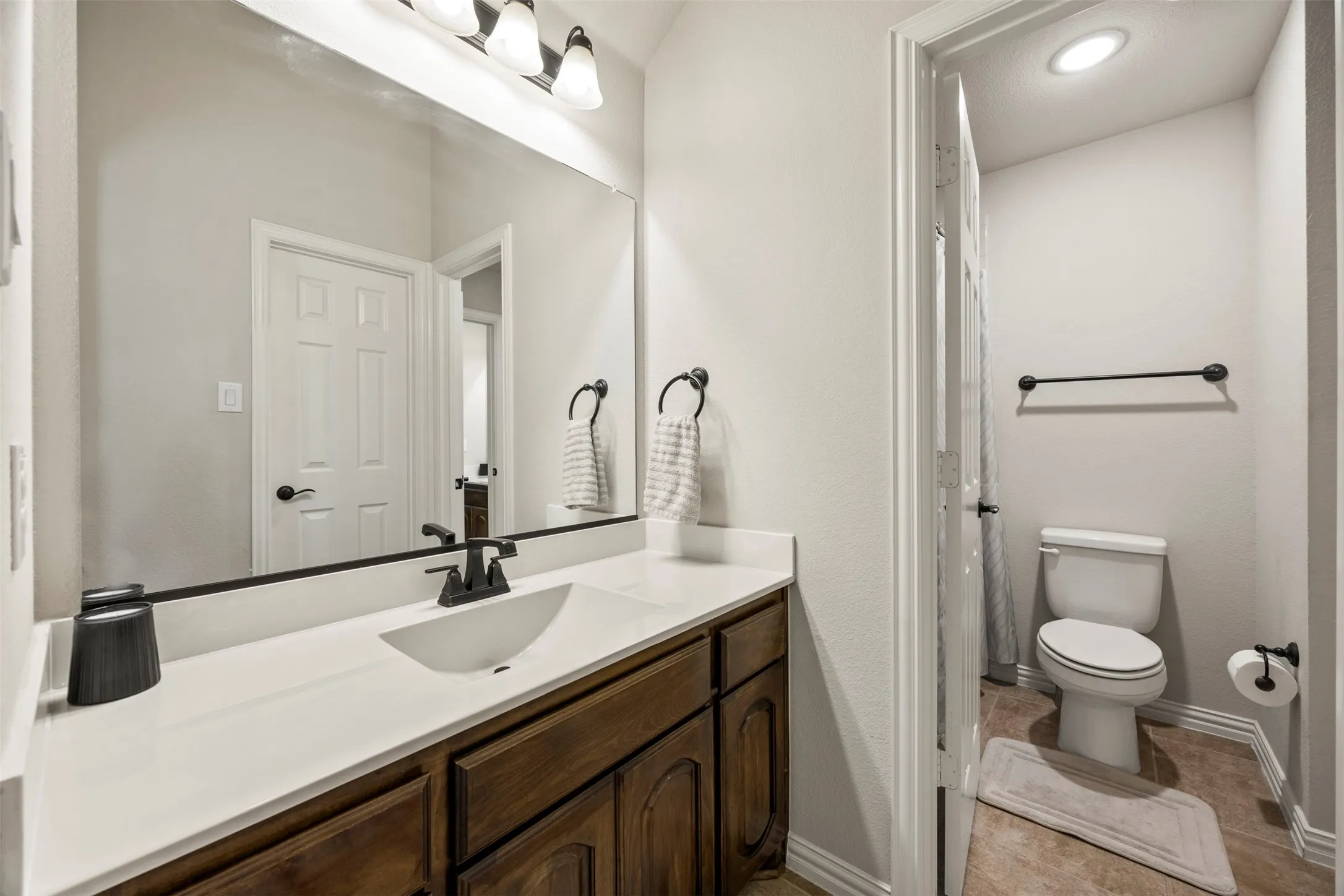 Bathroom vanity featuring a white countertop with an integrated sink, dark wood-finish cabinetry, and a black faucet
