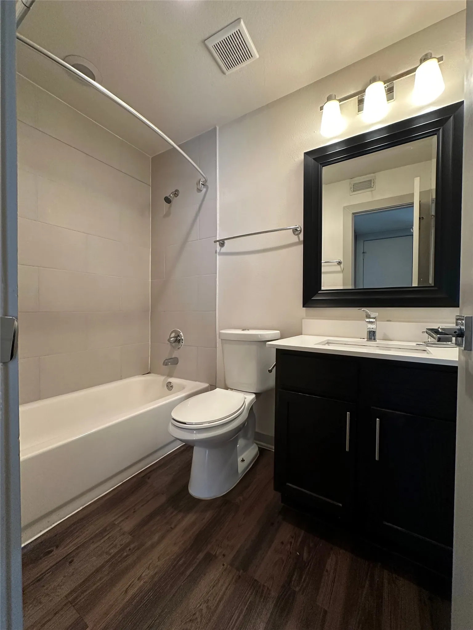 Bathroom featuring a vanity with dark cabinetry, white countertop, and a framed mirror