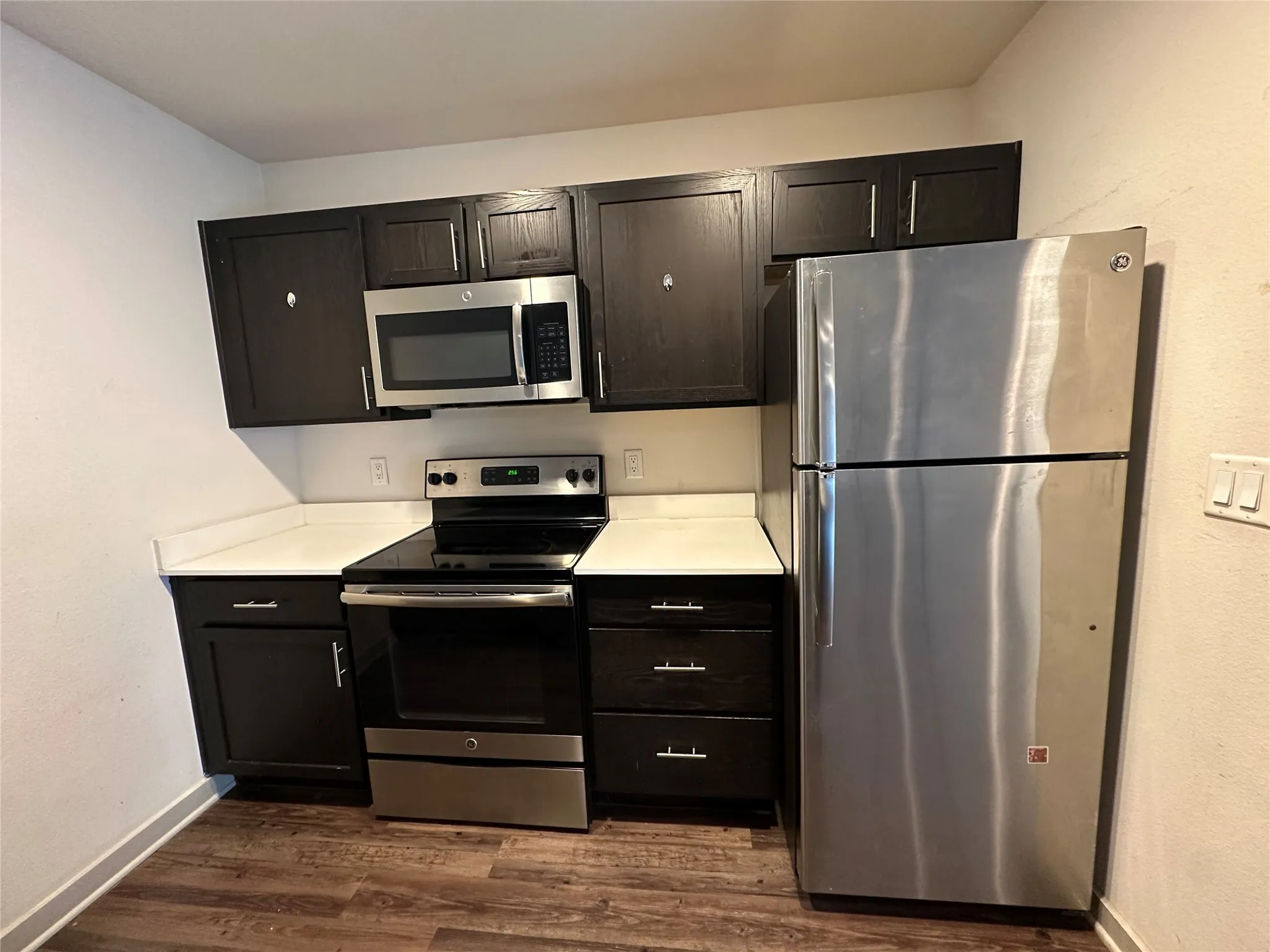 Kitchen featuring dark wood-finish cabinetry, white countertops, and wood-finish flooring