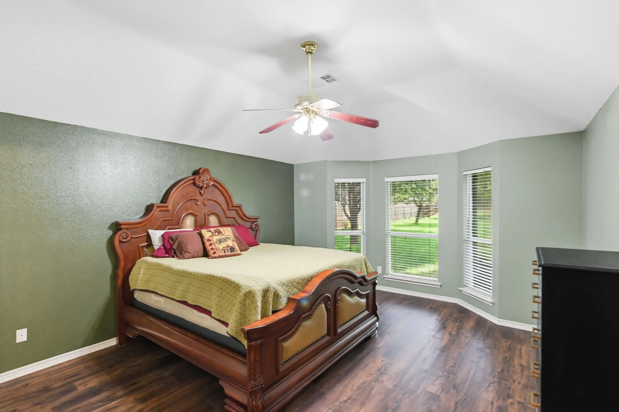 Spacious room featuring wood-finish flooring and a vaulted ceiling