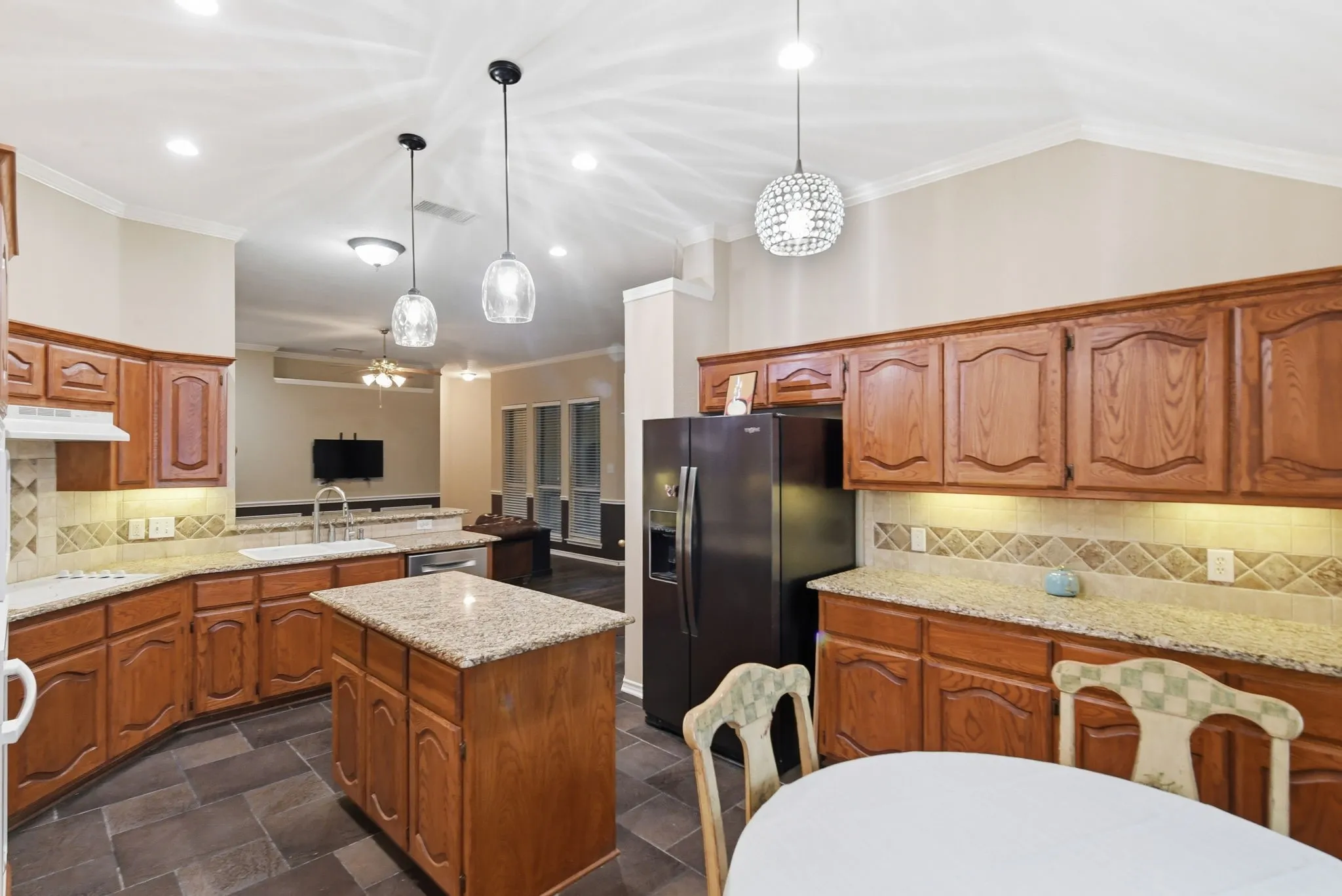 Kitchen featuring wood cabinetry, granite countertops, an undermount sink, a tiled backsplash, and recessed lighting